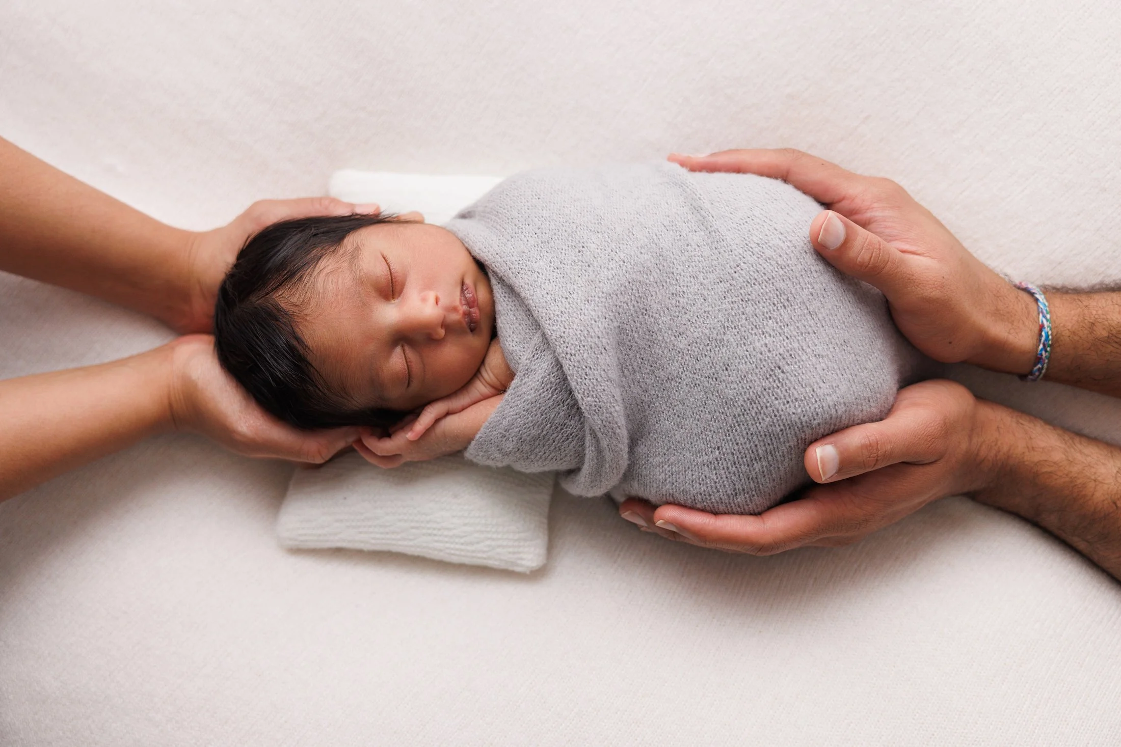 newborn baby with parents hand holding him
