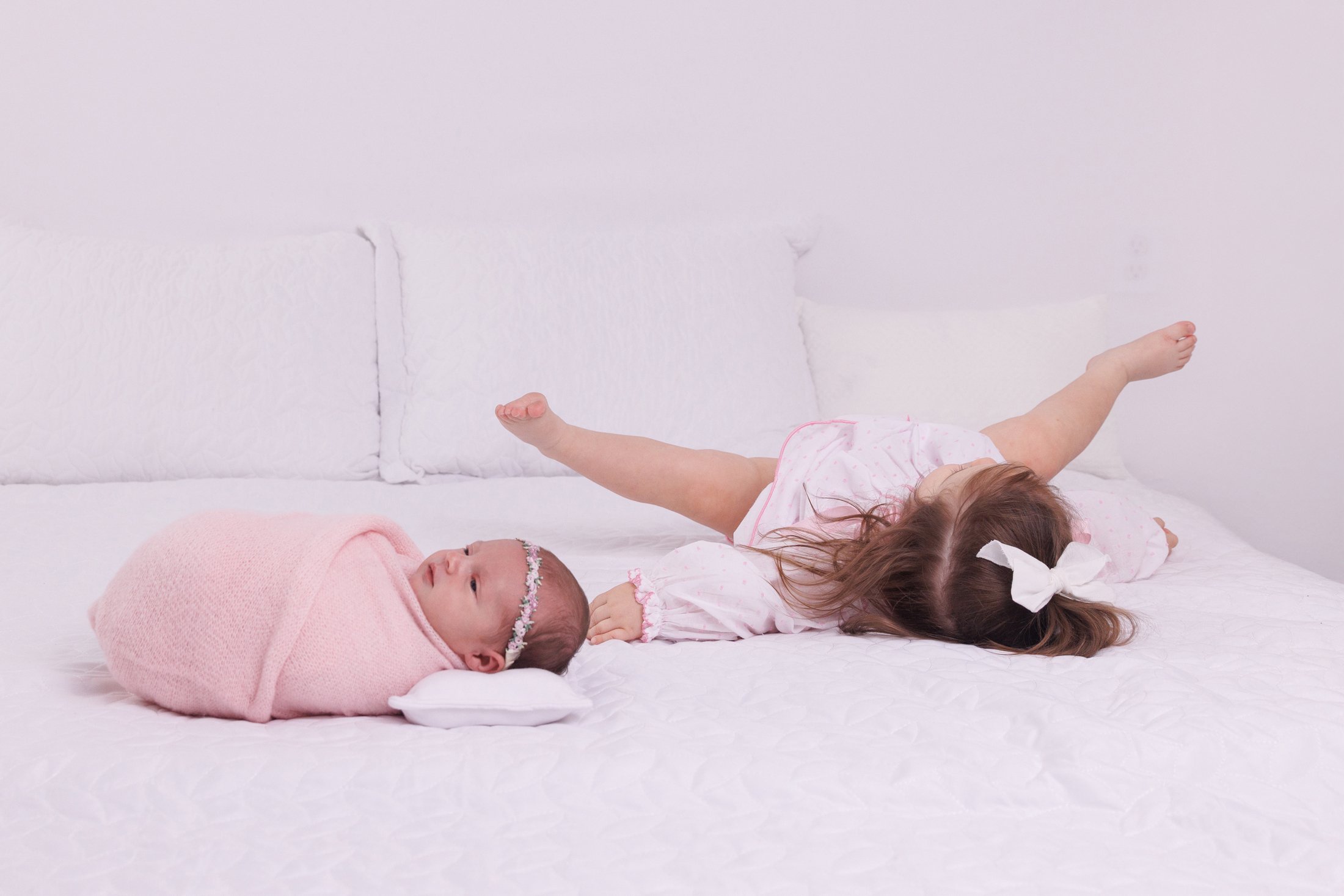 newborn baby with big sister on bed