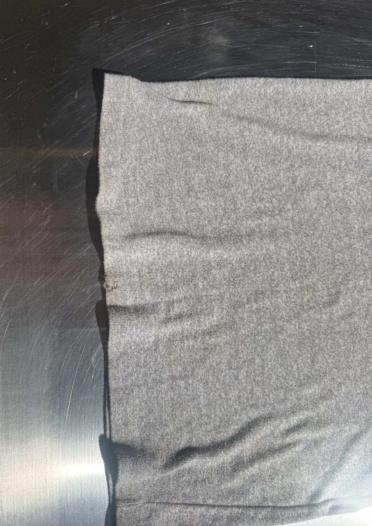 Hem detail on vintage grey ICA jersey t-shirt showing small hole