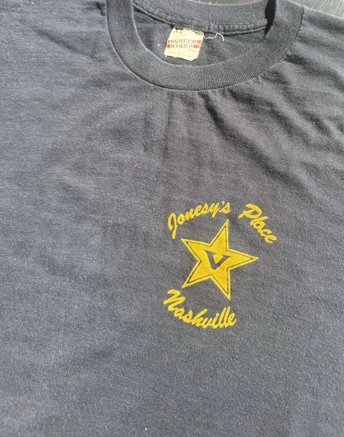 Close-up of yellow Jonesy's Place Nashville star print and Screen Stars neck label
