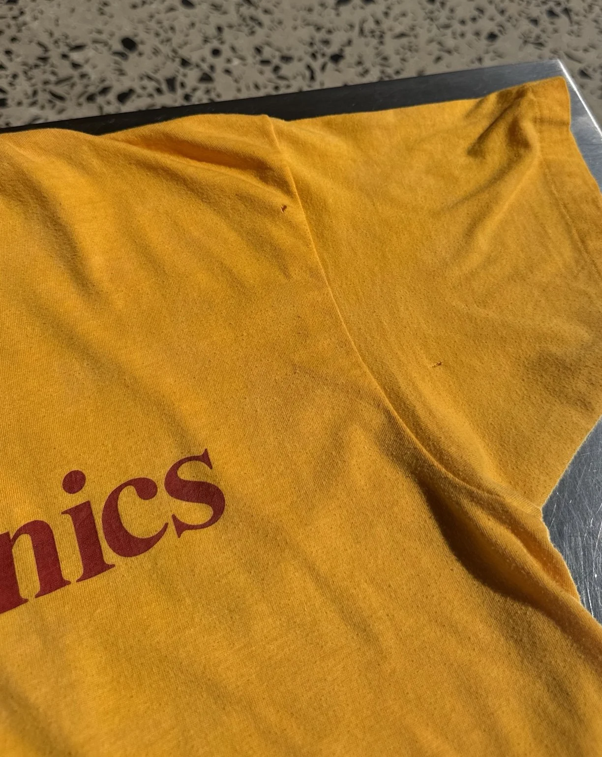 Close-up of red Injectronics print and 50/50 cotton poly fabric on vintage 80s yellow t-shirt