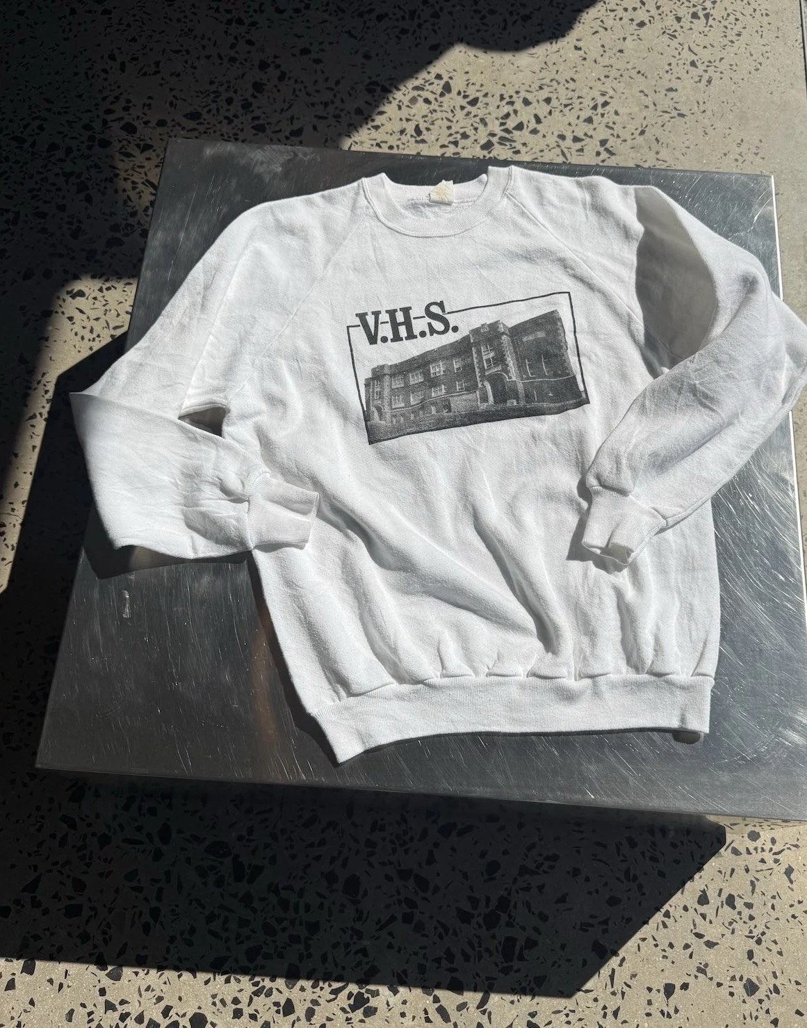Vintage white V.H.S. school sweatshirt laid flat showing raglan sleeves and front print