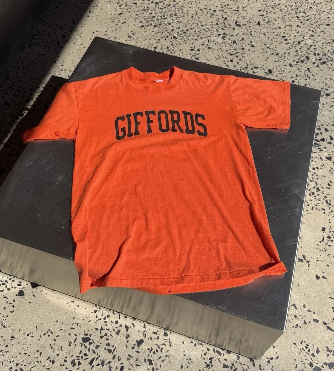 Vintage 80s orange Giffords t-shirt laid flat showing full front print