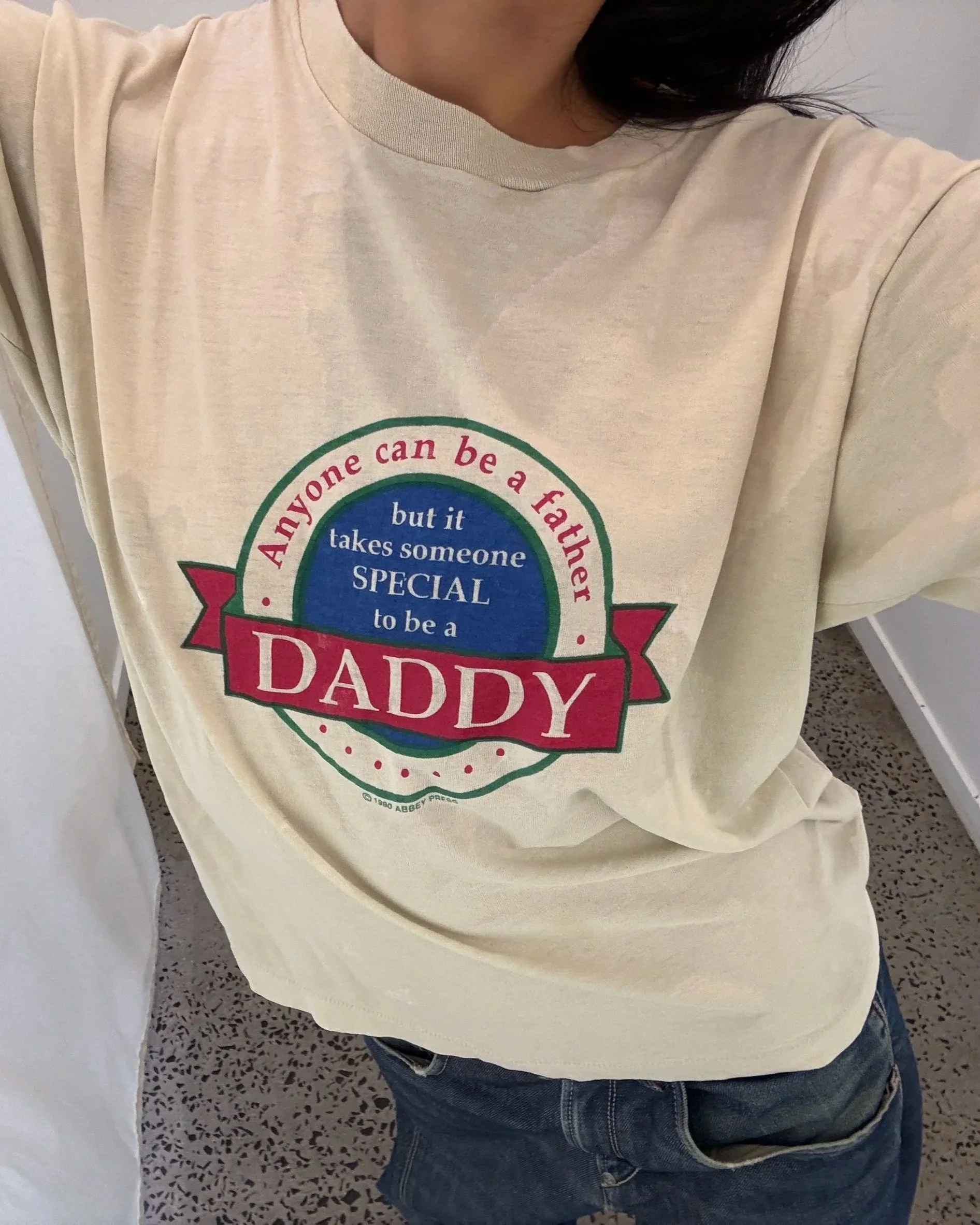 Model wearing a vintage 90s cream t-shirt with red and blue crest print
