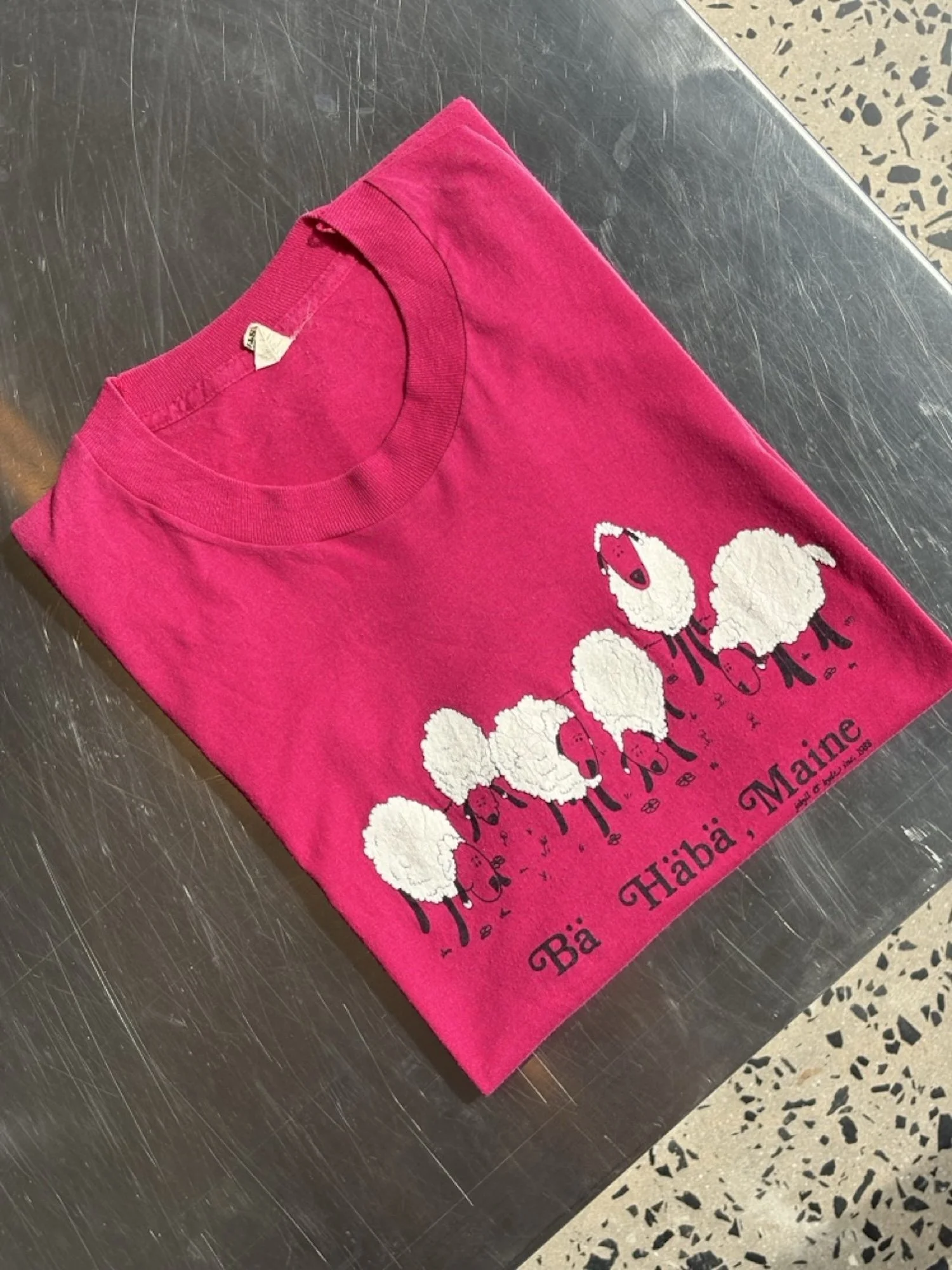 Close-up of white sheep print and Bä Häbä, Maine lettering on vintage pink t-shirt
