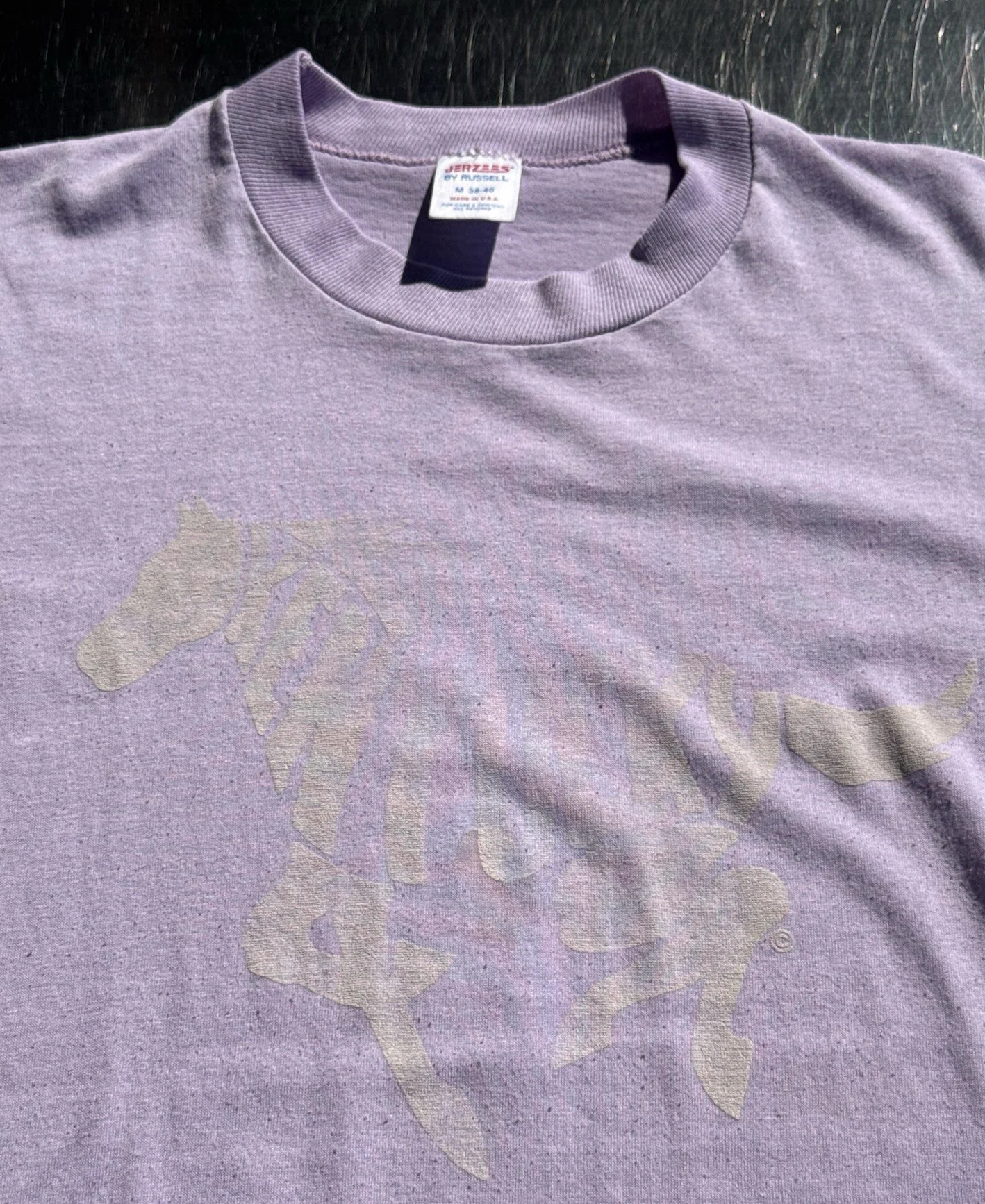 Close-up of faded horse print and Jerzees by Russell neck label on vintage lilac t-shirt