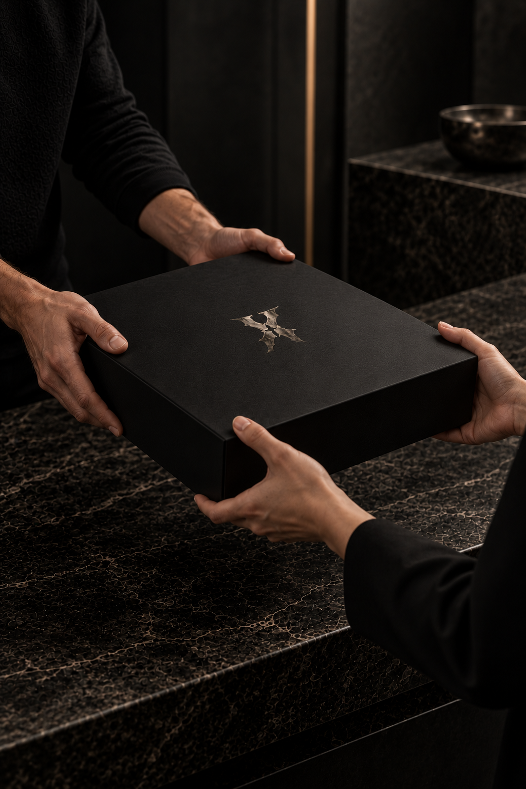 Customer handing a black Ten-Chapters return box with a metallic X logo to a store representative.
