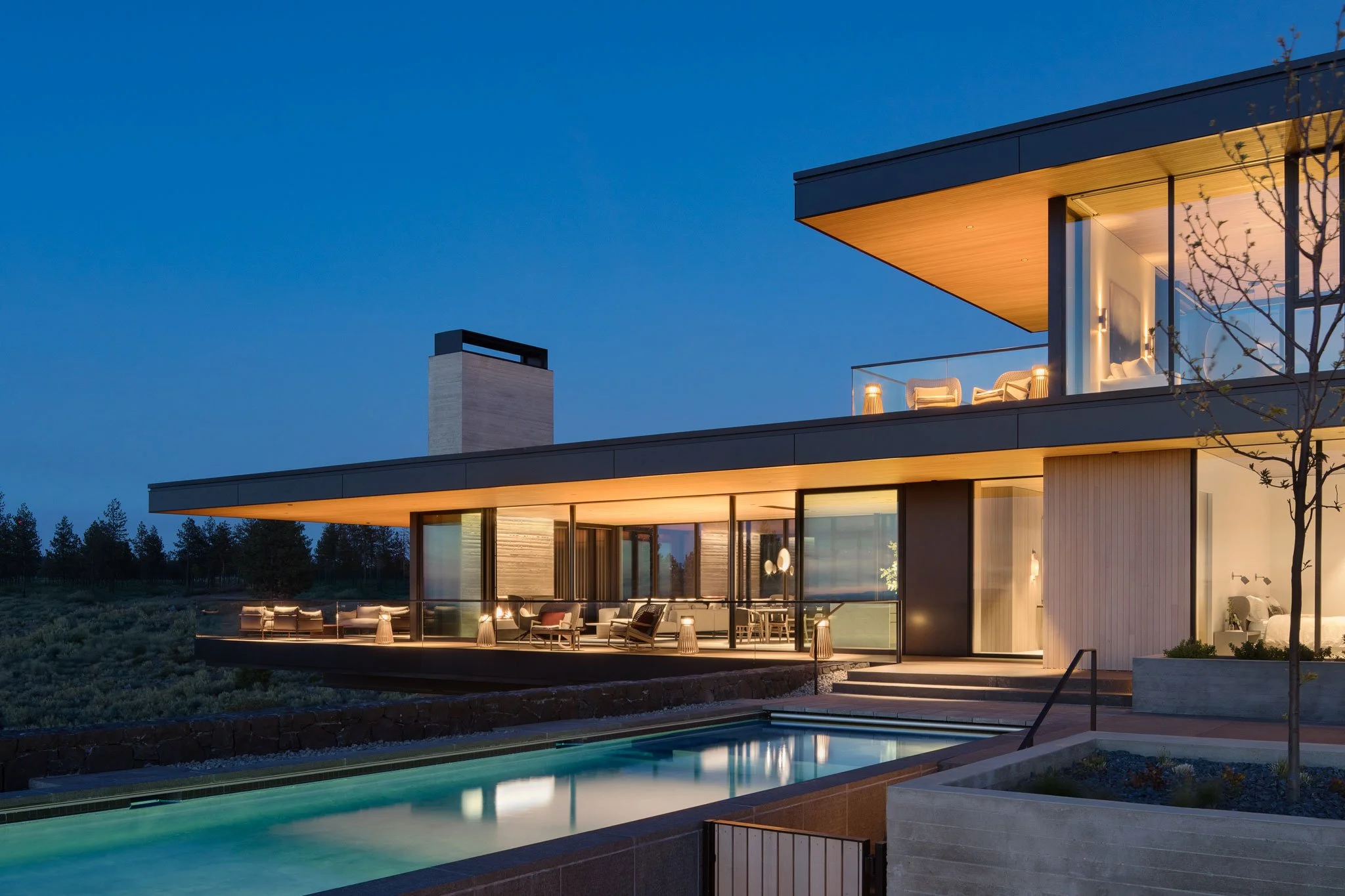 Backyard view of pool and living room with floor to ceiling windows