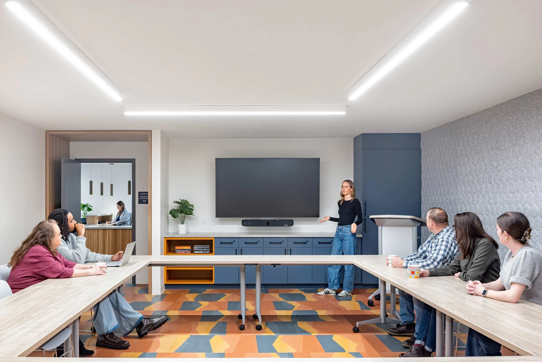Conference and meeting room with colorful graphic flooring with TV on wall