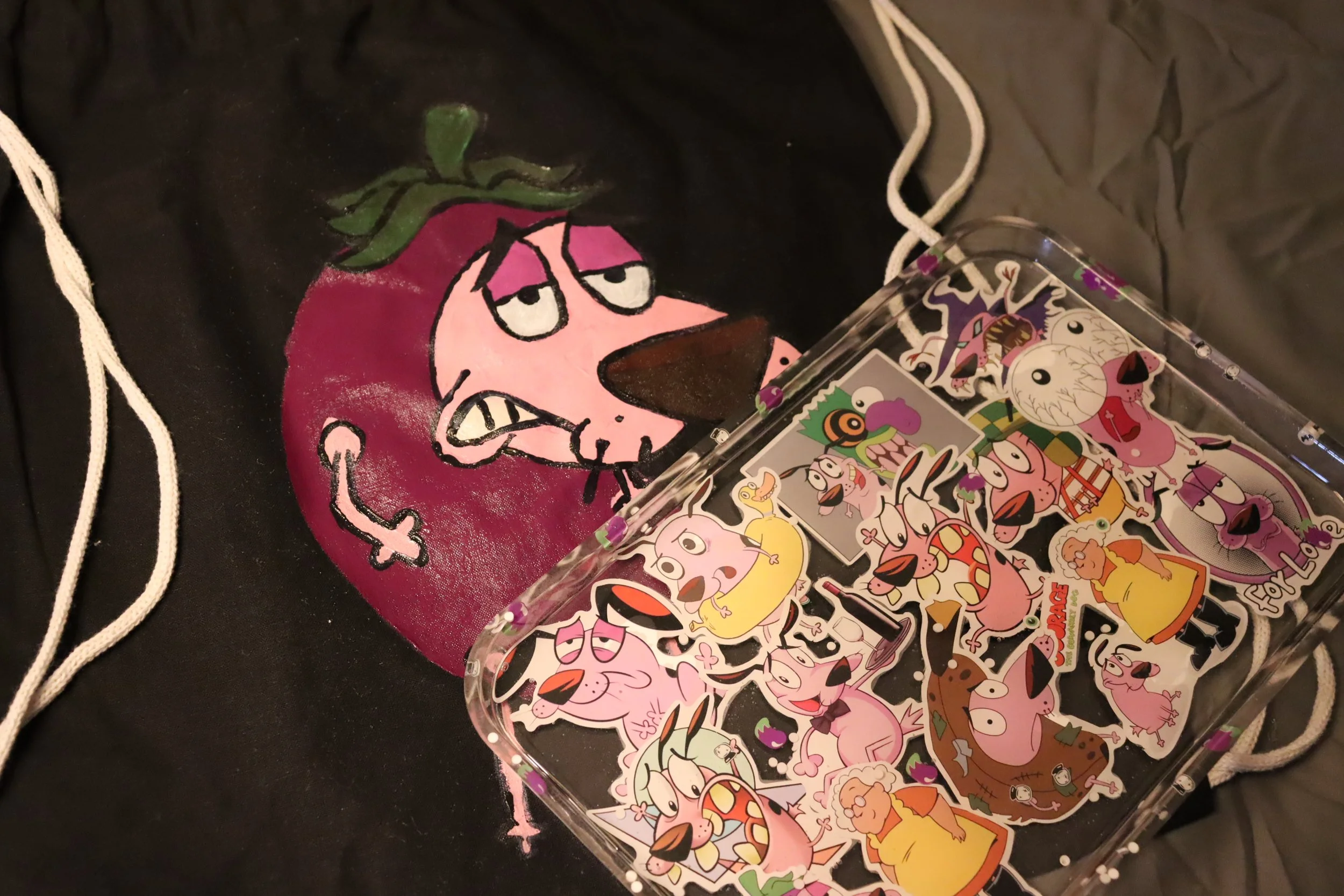 Black hoodie with Pinky and the Brain characters embroidered on it, surrounded by a collection of sticker sheets with various cartoon characters.