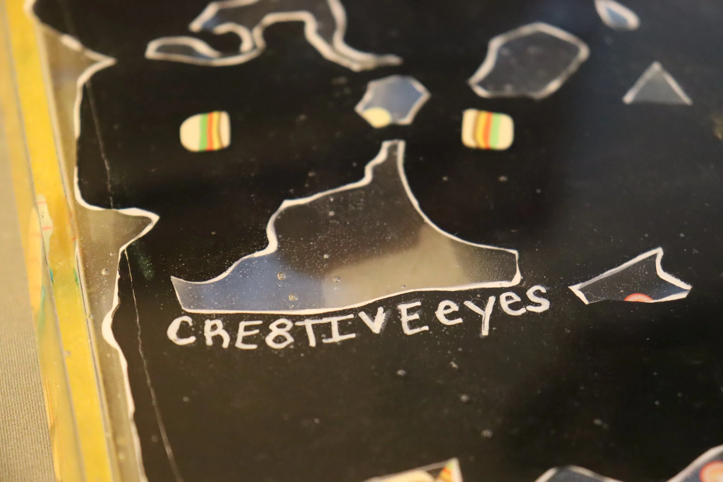 Close-up of a package with black, white, and rainbow-colored chips shaped like eyes, with text reading 'CRESTVIEW EYES' and partially visible yellow packaging on the side.