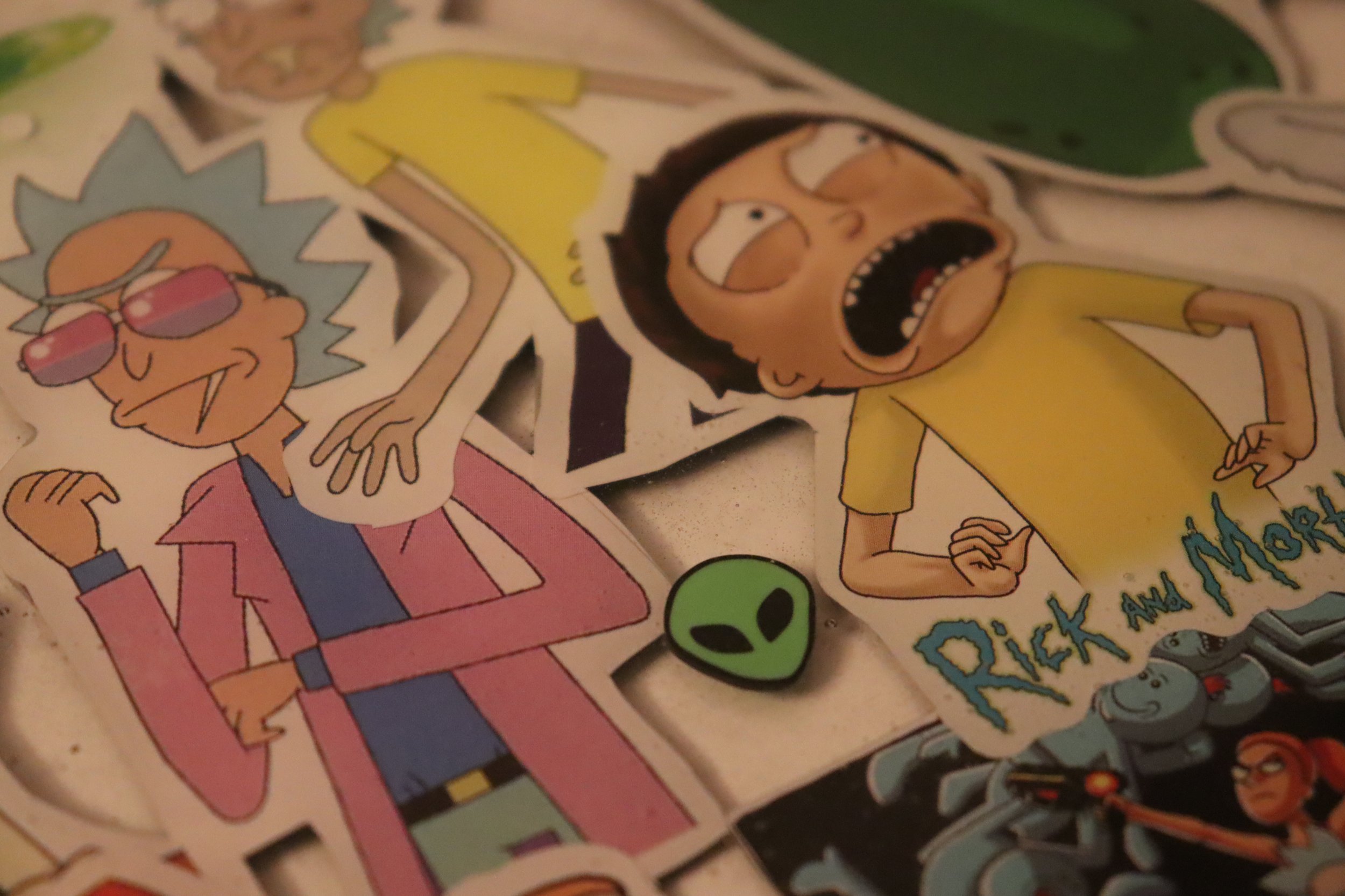 Colorful cartoon stickers on a surface, featuring characters with exaggerated facial expressions, including Rick from Rick and Morty wearing sunglasses, and a person with an open mouth and hands on their hips.