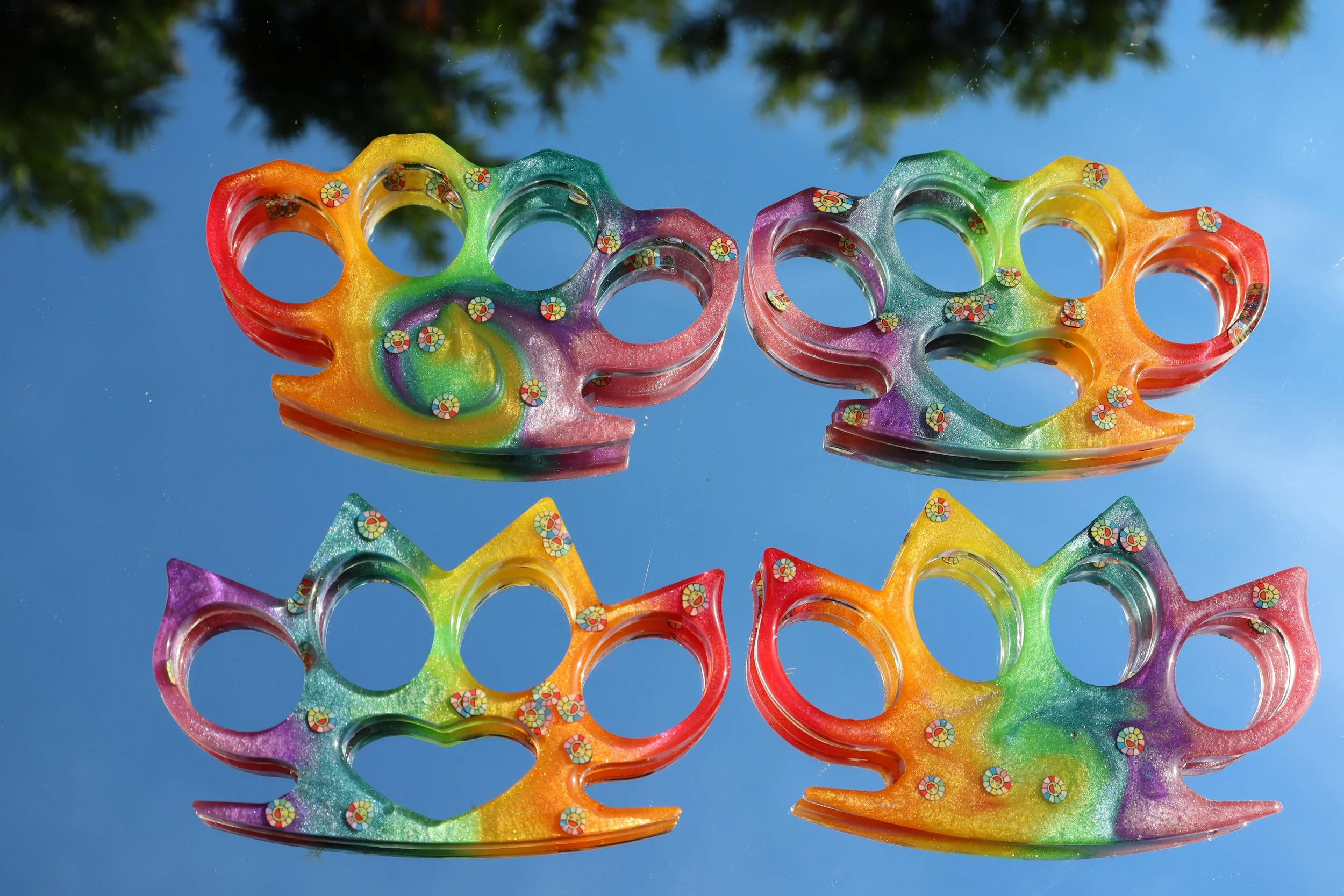 Colorful plastic knuckles stacked against a bright blue sky with trees in the background.