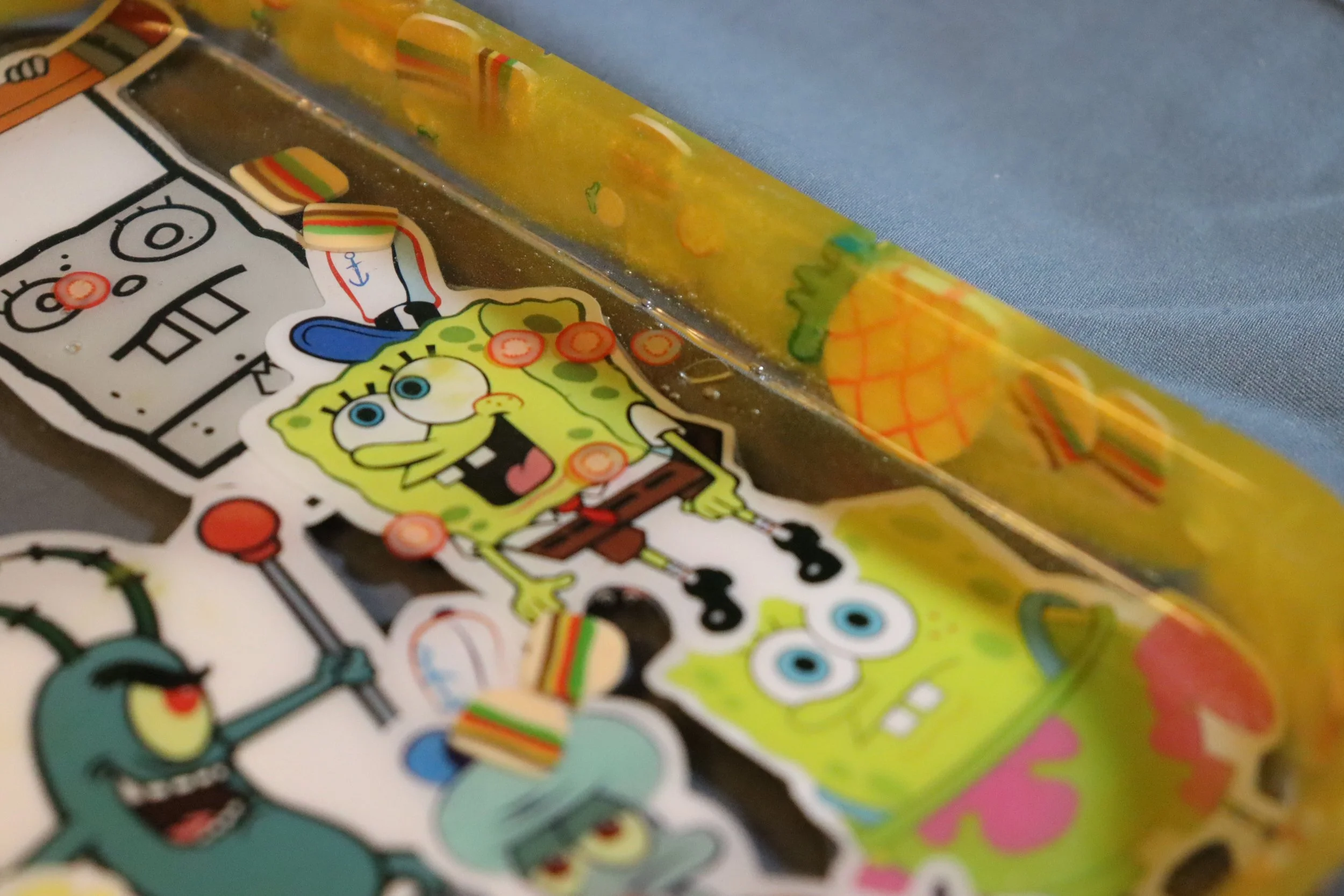 Colorful stickers featuring cartoon characters, including SpongeBob SquarePants, are scattered on a surface. Some stickers are partially peeled or overlapping.