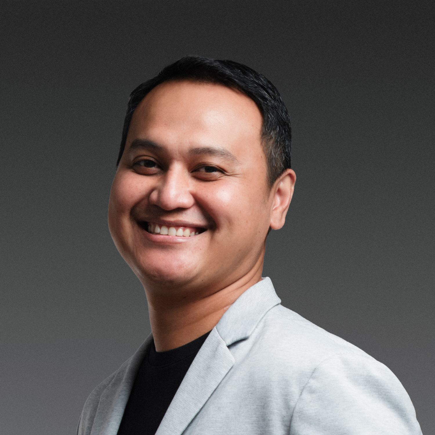 Smiling person wearing a gray shirt against a white background.