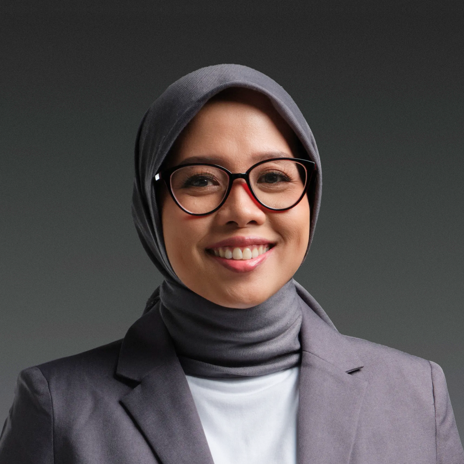 Person wearing glasses and a black hijab smiling against a white background.