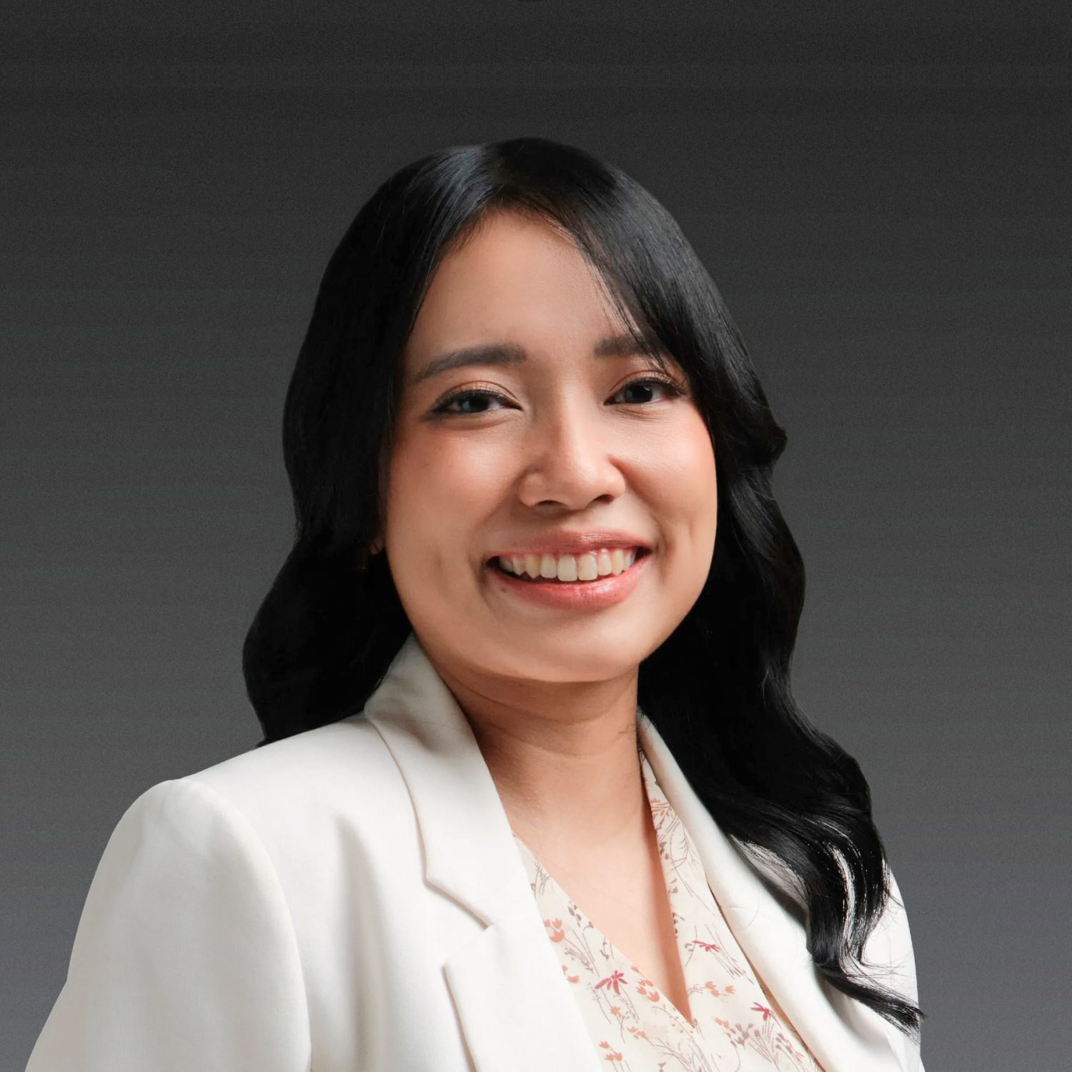 Smiling person wearing a black hijab and white coat on a white background.