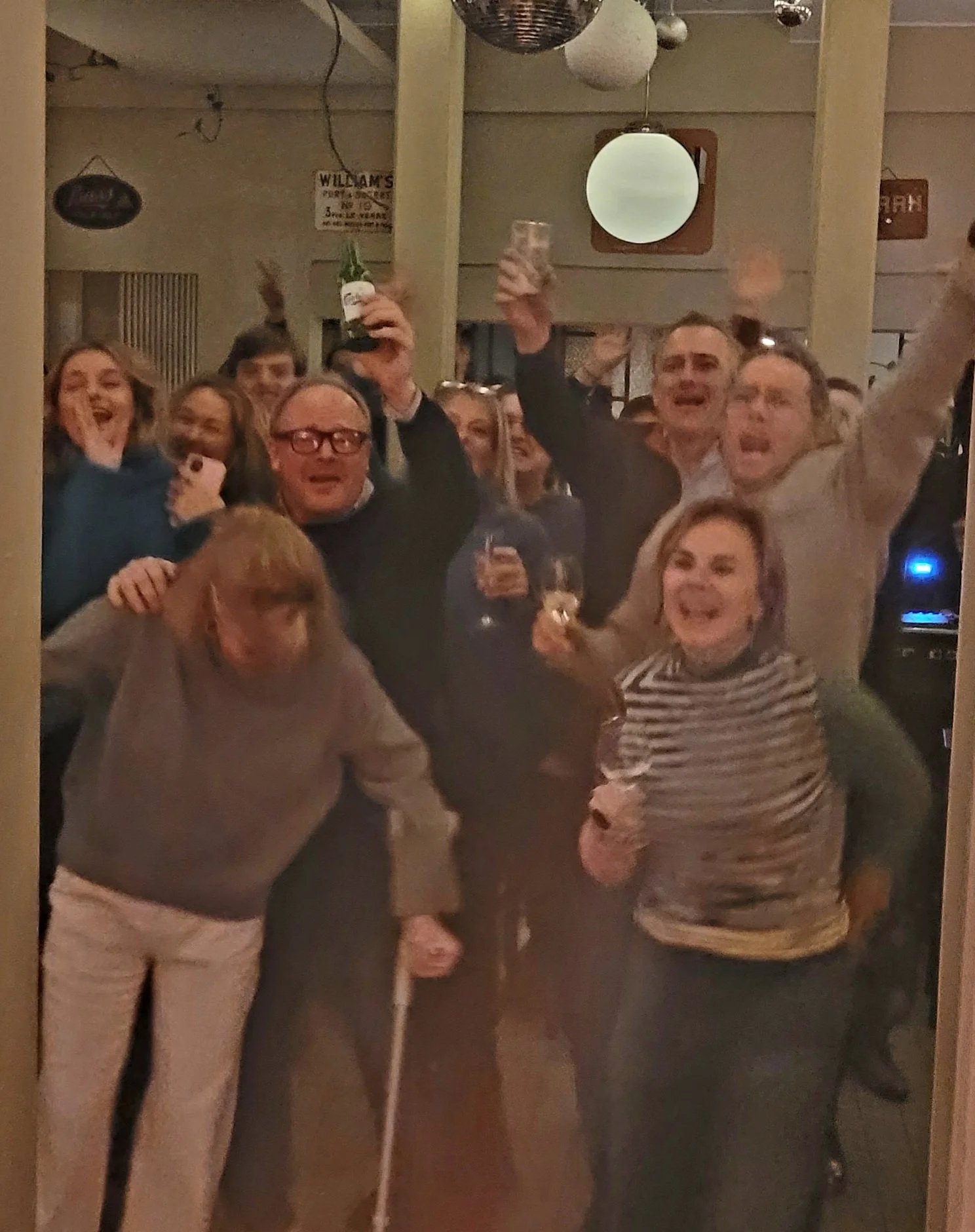 Groep mensen die feest vieren met drinks, lachend en dansend.