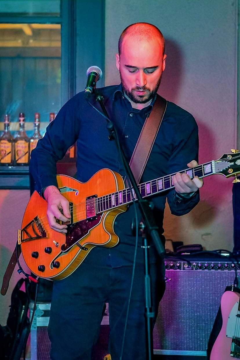 Man die gitaar speelt en zingt in een bar of club.