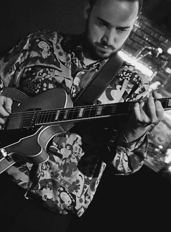 Man die gitaar speelt in een donkere omgeving.