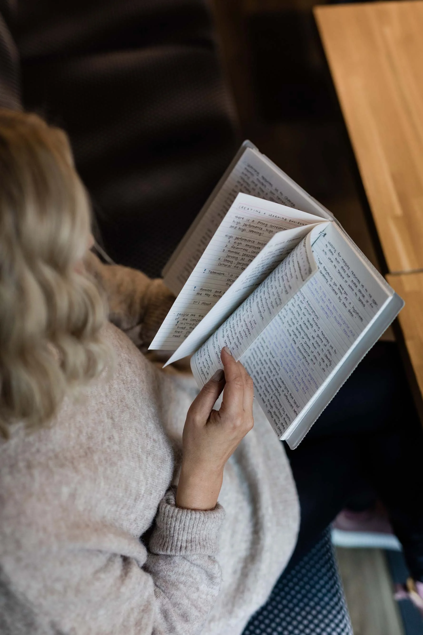 Muutosvalmius Camilla Havanka lukee kirjaa, istuu todennäköisesti luokkahuoneessa, takana näkyy istuimia ja osittain näkyvä pöytä.