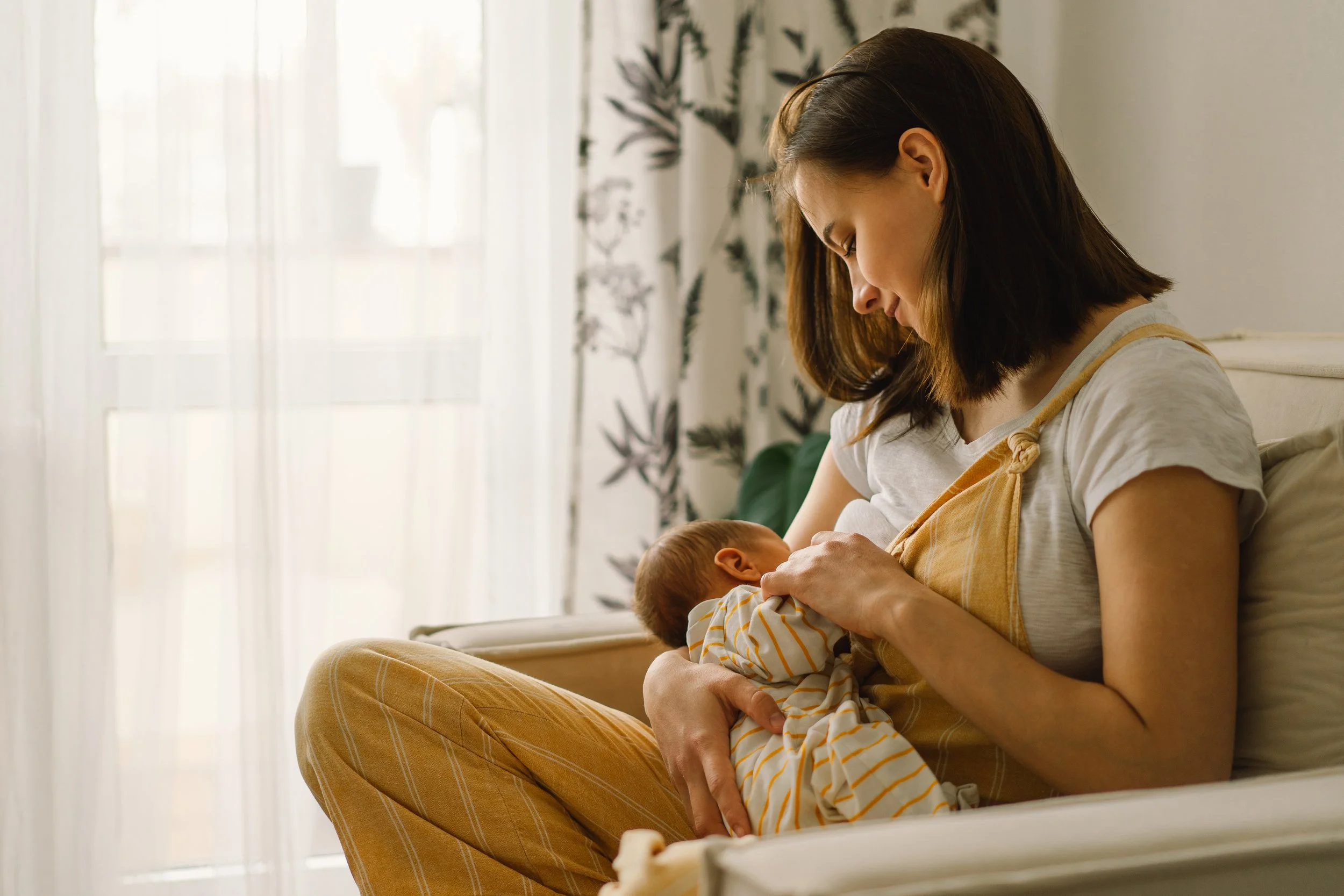 Mother breastfeeding baby in a cozy room.