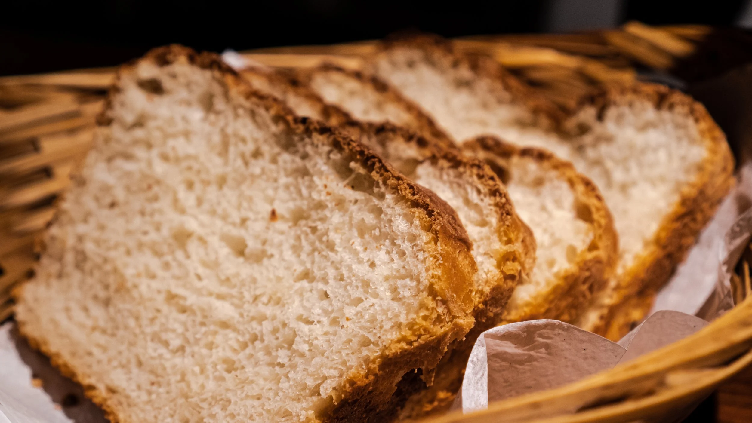 Slices of bread in a wicker basket lined with white paper.