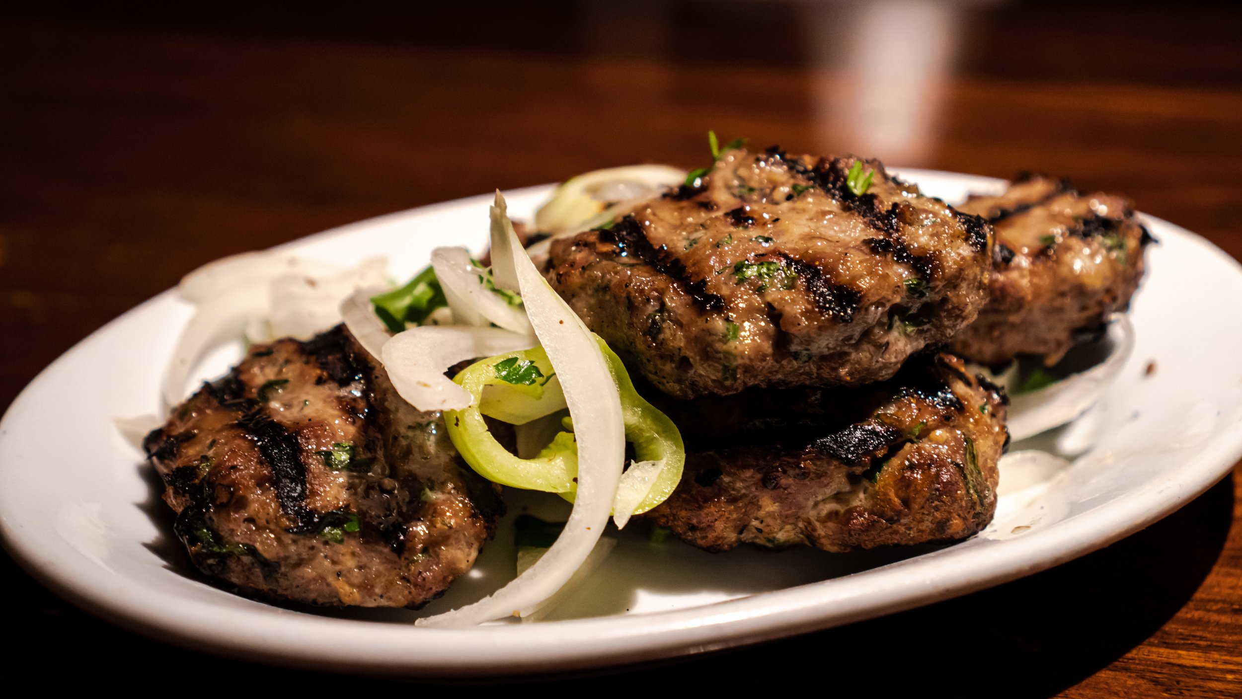 Grilled kebabs with sliced onions and green herbs on a white plate