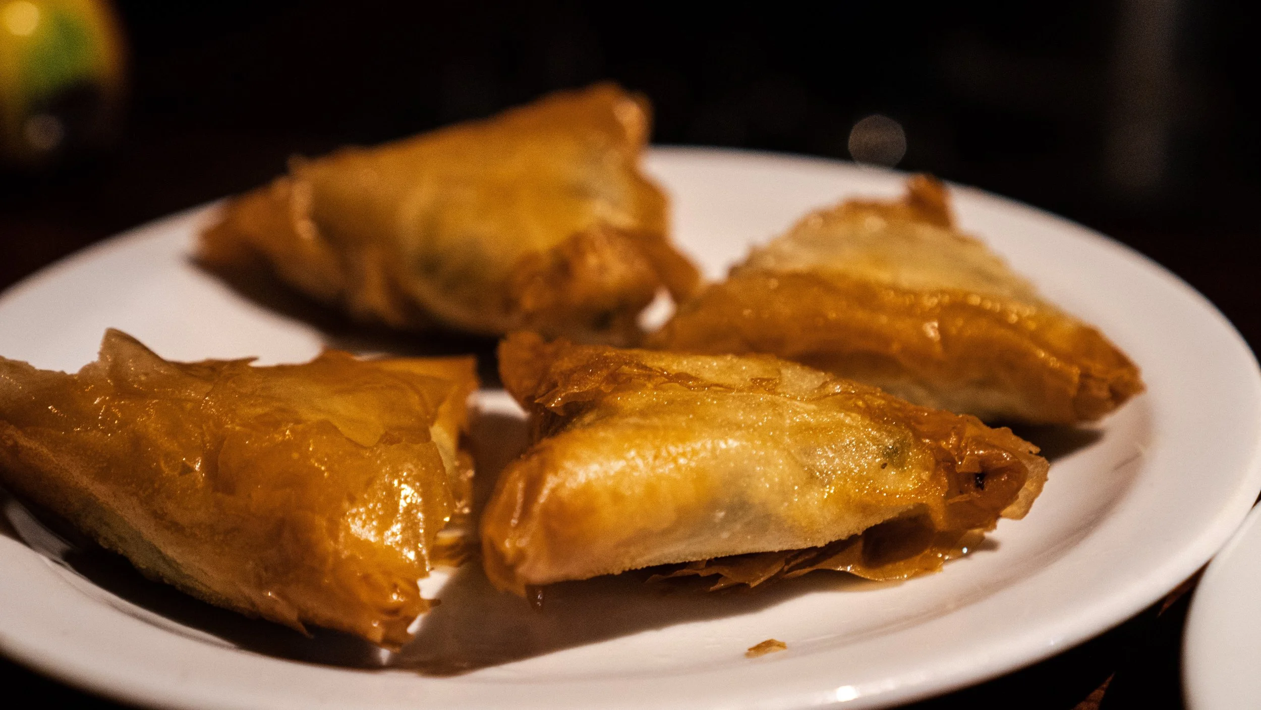 Four deep fried spanakopita on a white plate, golden-brown crispy exterior