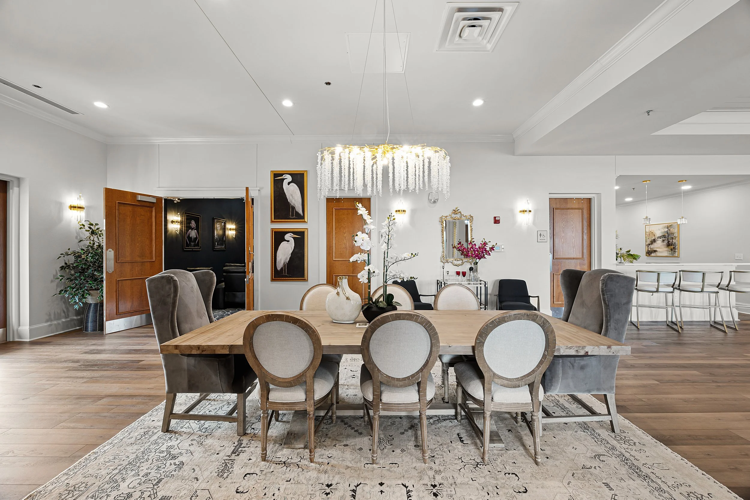 Large wooden dining table with grey wingback and round chairs.