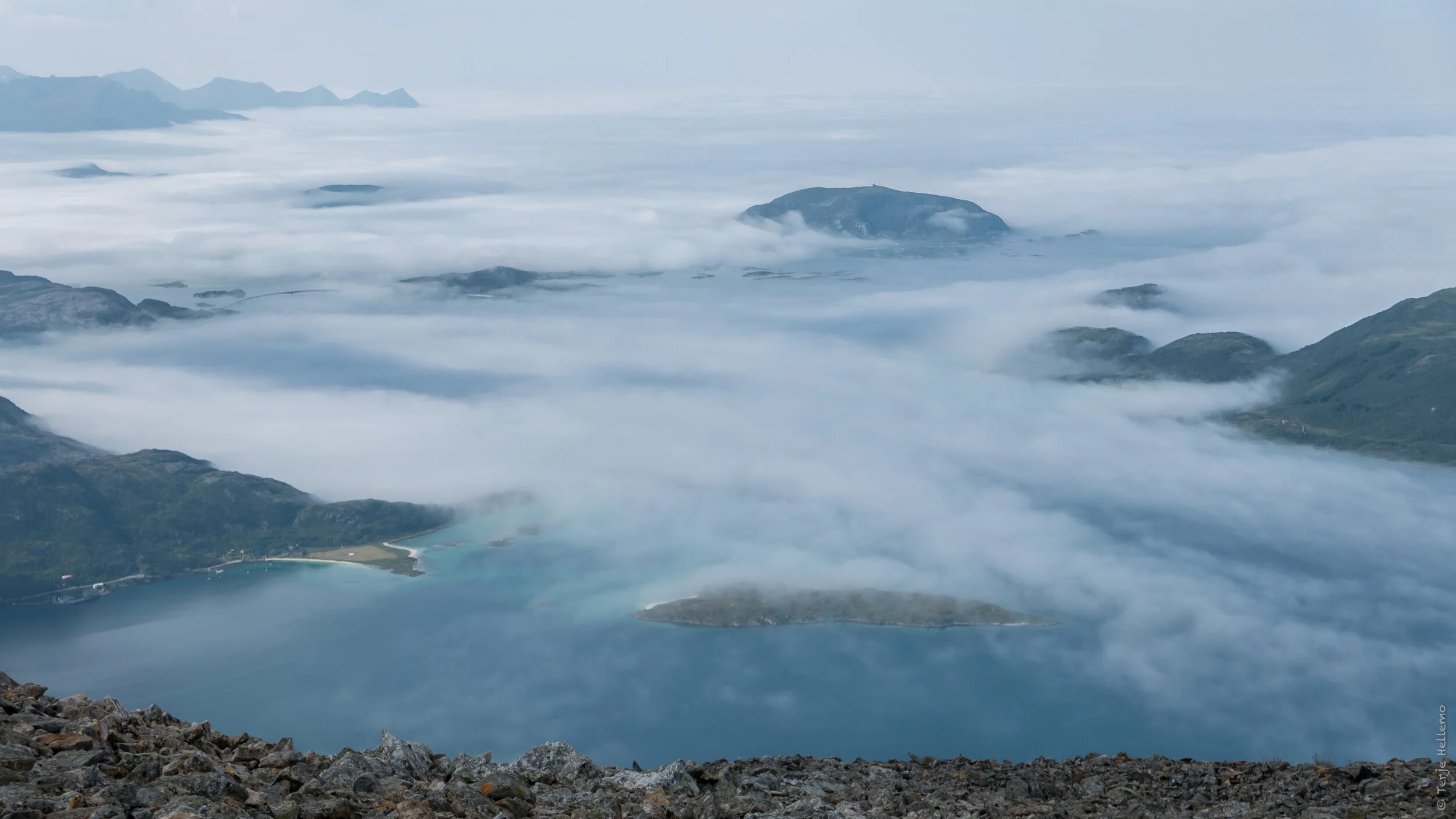 Sommarøya er dekket av skodde. Hillesøya stikker opp. I bakgrunnen kan vi se Senja.