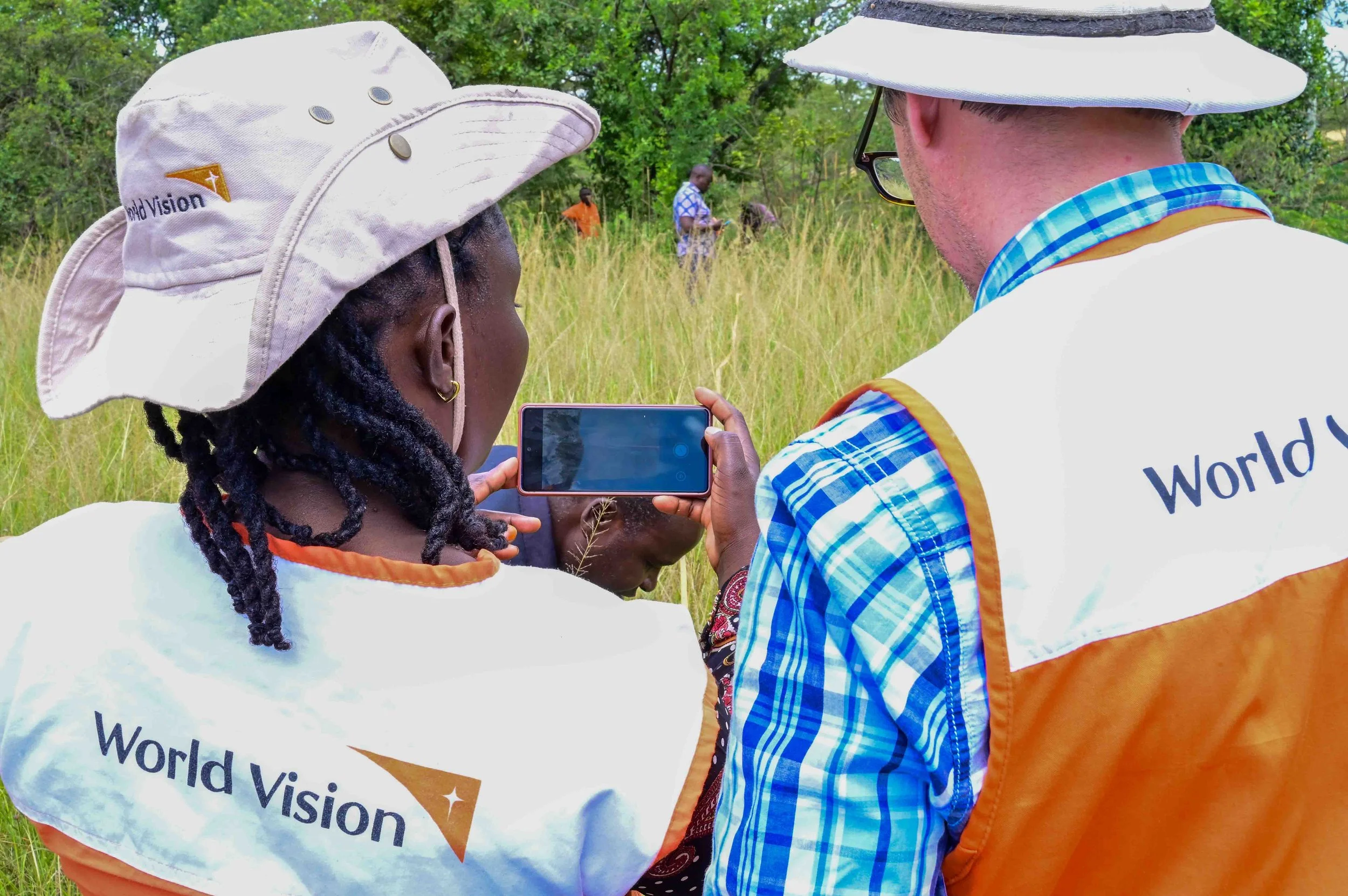 World Vision colleagues using a mobile device to monitor a restoration site in Kenya