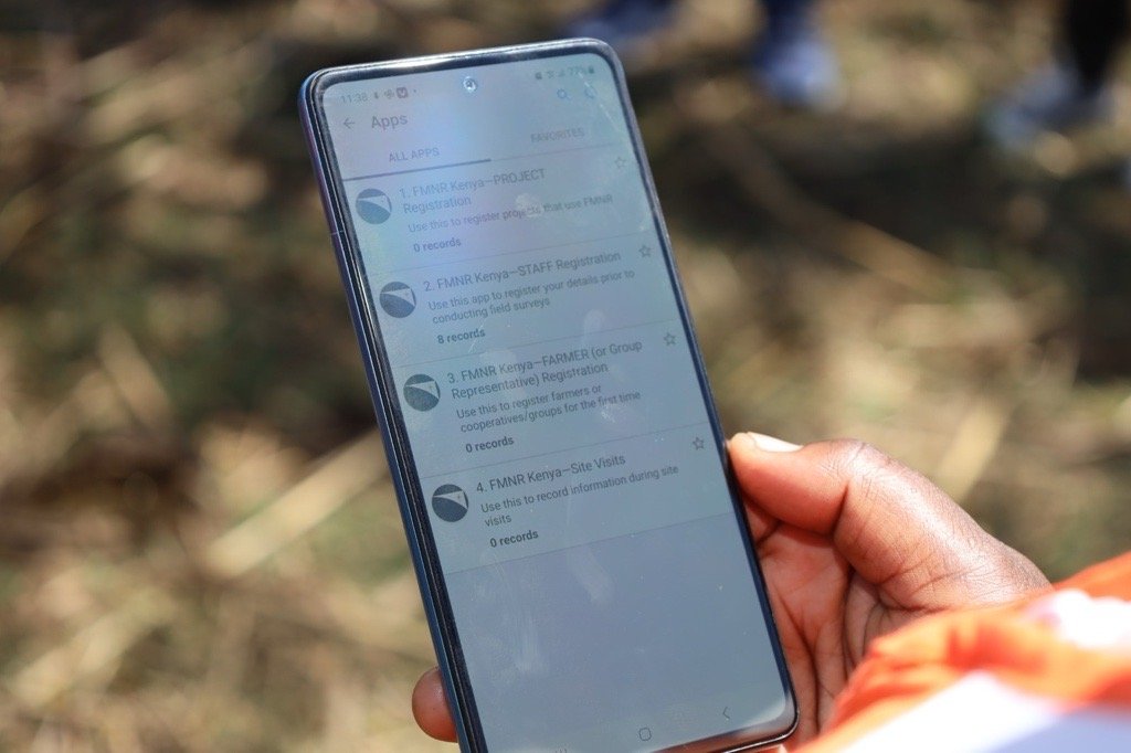 Field worker holding a phone with a Solstice monitoring survey open