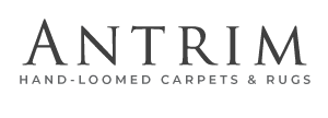 Antrim Hand-Loomed Carpets and Rugs logo with black background and white text.