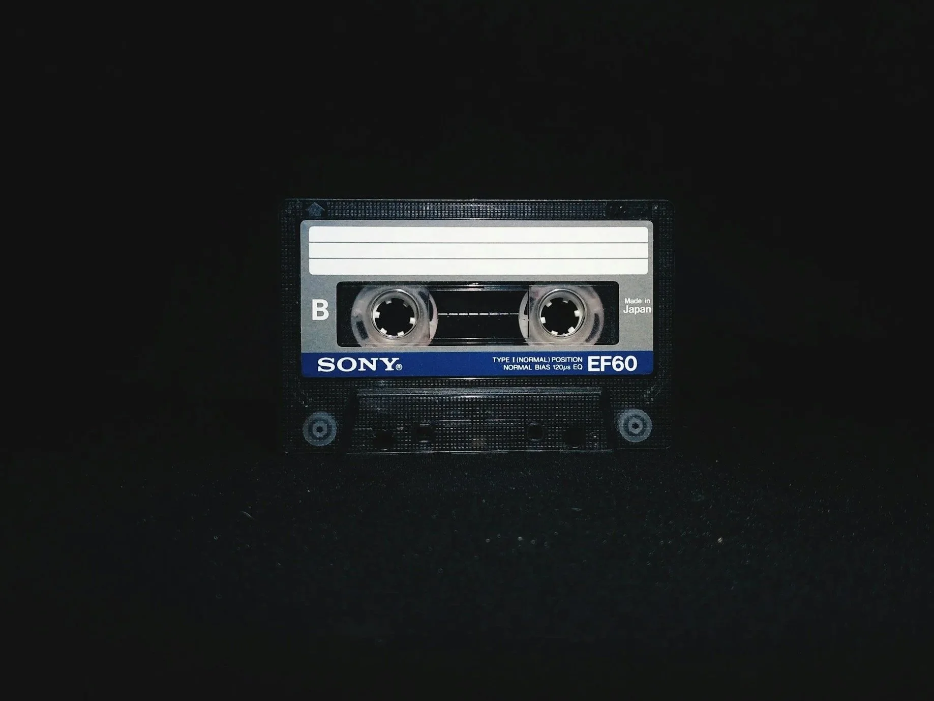 A black cassette tape with a blue and white label, labeled 'Sony dark background.