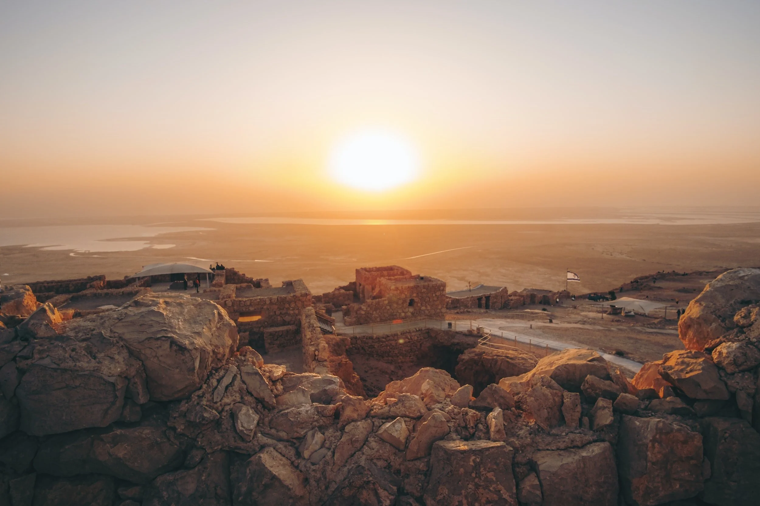 Sunset over ancient stone ruins on a desert landscape.