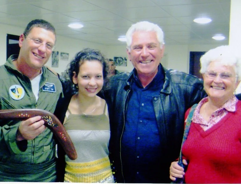 Group of five smiling people indoors, with one holding a snake.