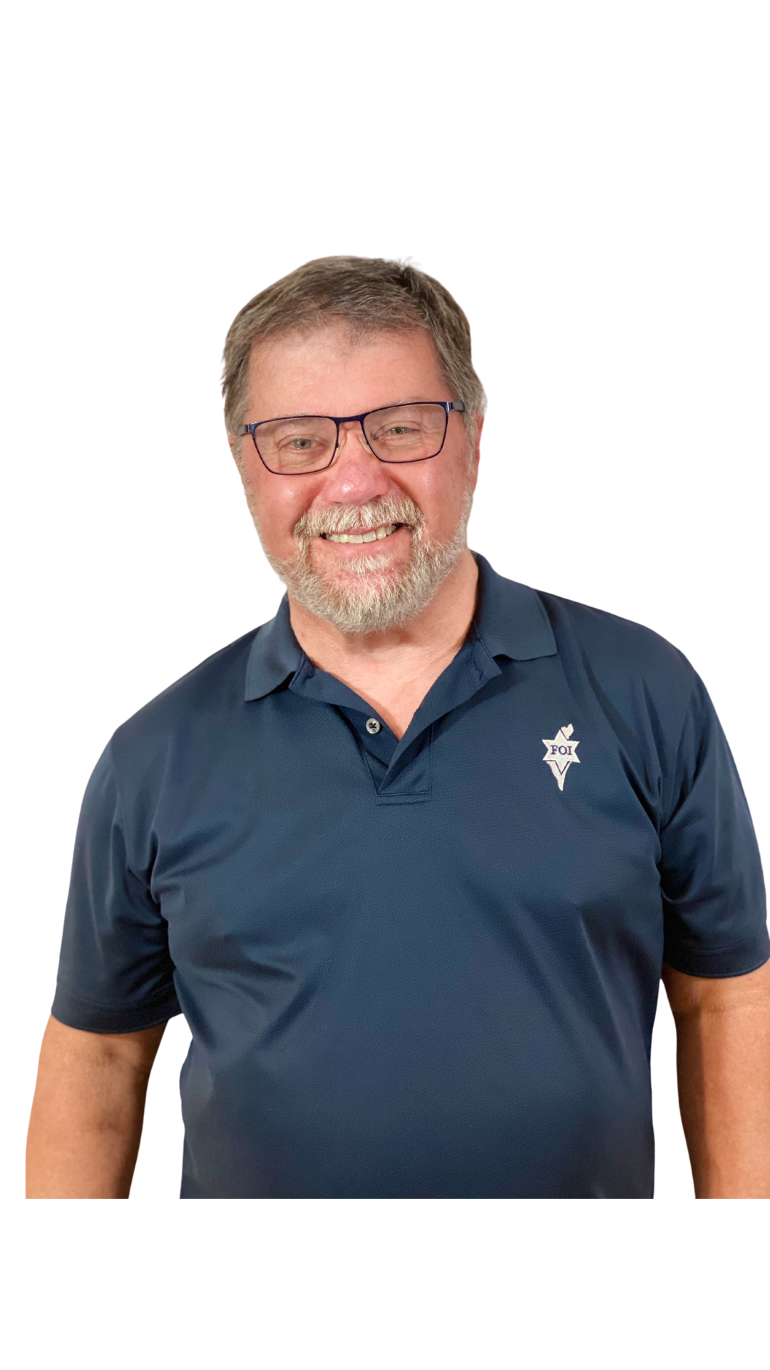 A middle-aged man with glasses, beard, and mustache smiling, wearing a navy blue polo shirt with a badge logo on the chest.