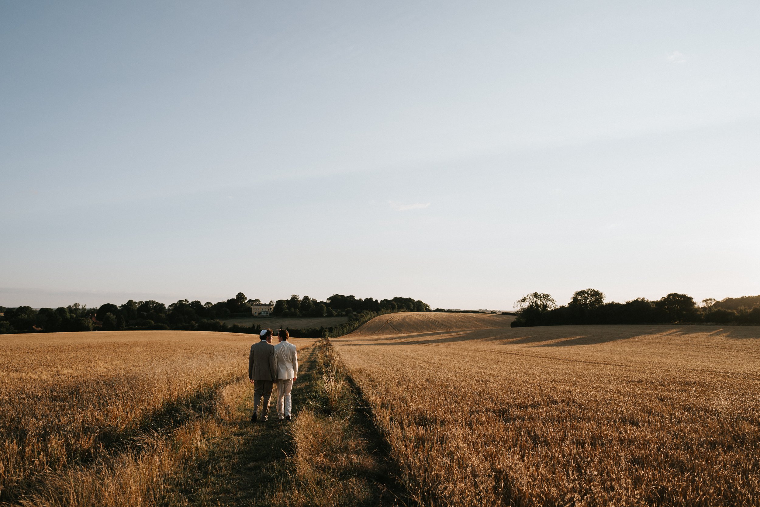 Two grooms walking at golden hour on their wedding day