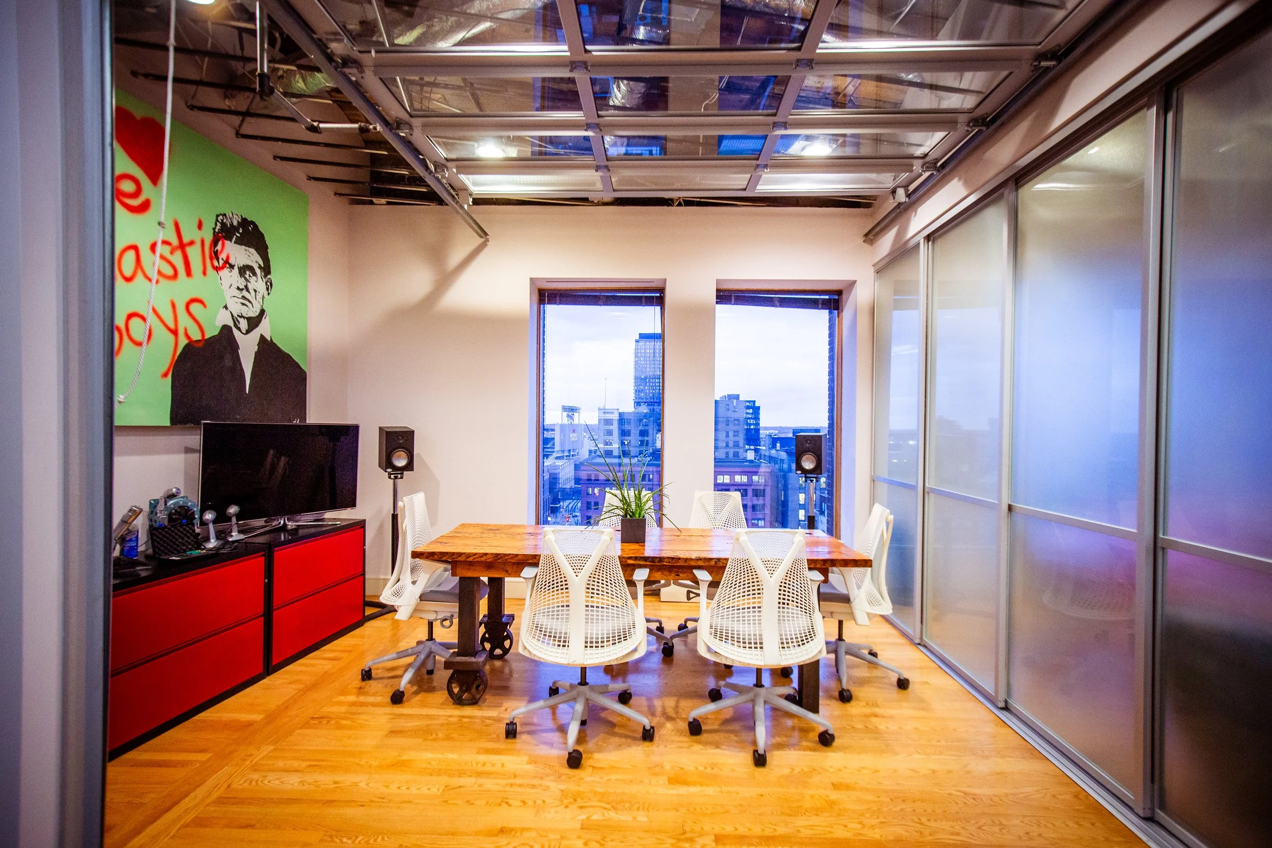 Bright client meeting and break room designed for collaboration, featuring seating for up to six, natural light, and adjustable glass garage-style doors for privacy.