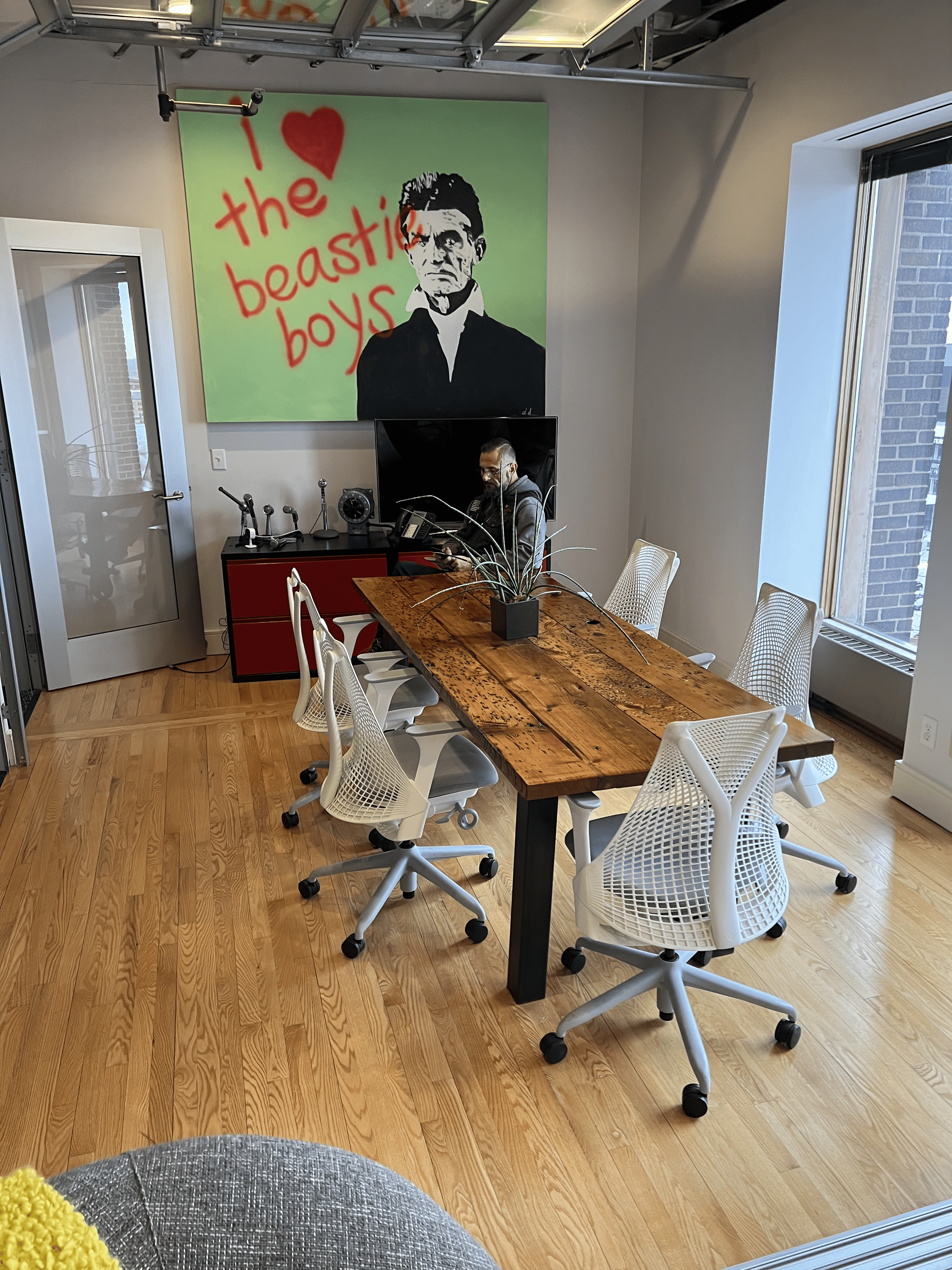 Bright client meeting and break room designed for collaboration, featuring seating for up to six, natural light, and adjustable glass garage-style doors for privacy for phone calls, meetings, or just a lunch break..