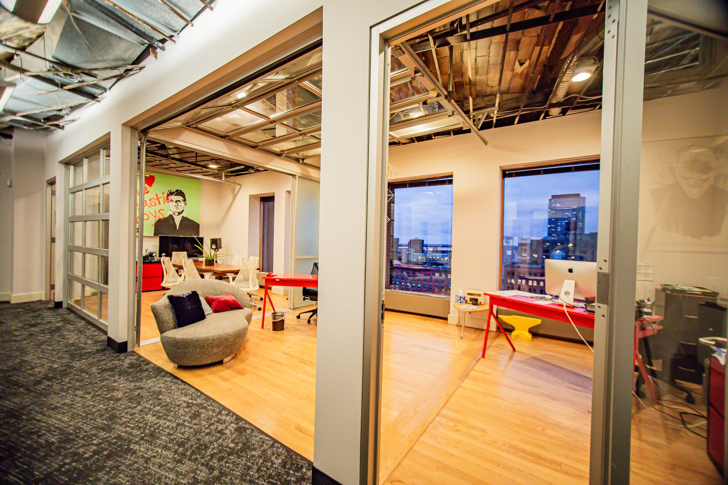 Angled view of the SisterBoss studio office featuring a red desk, workspace seating, and natural light.