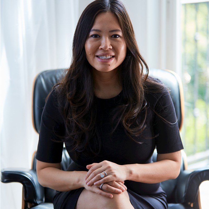 Photo of Tan Le in a black top sitting on a black chair.
