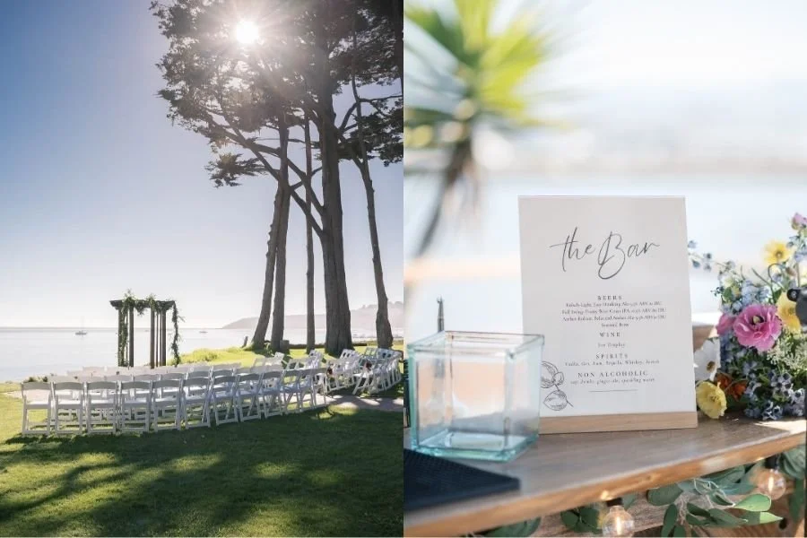 Outdoor wedding setup by the sea with white chairs facing an arbor under tall trees, and a bar menu on a table adorned with colorful flowers.