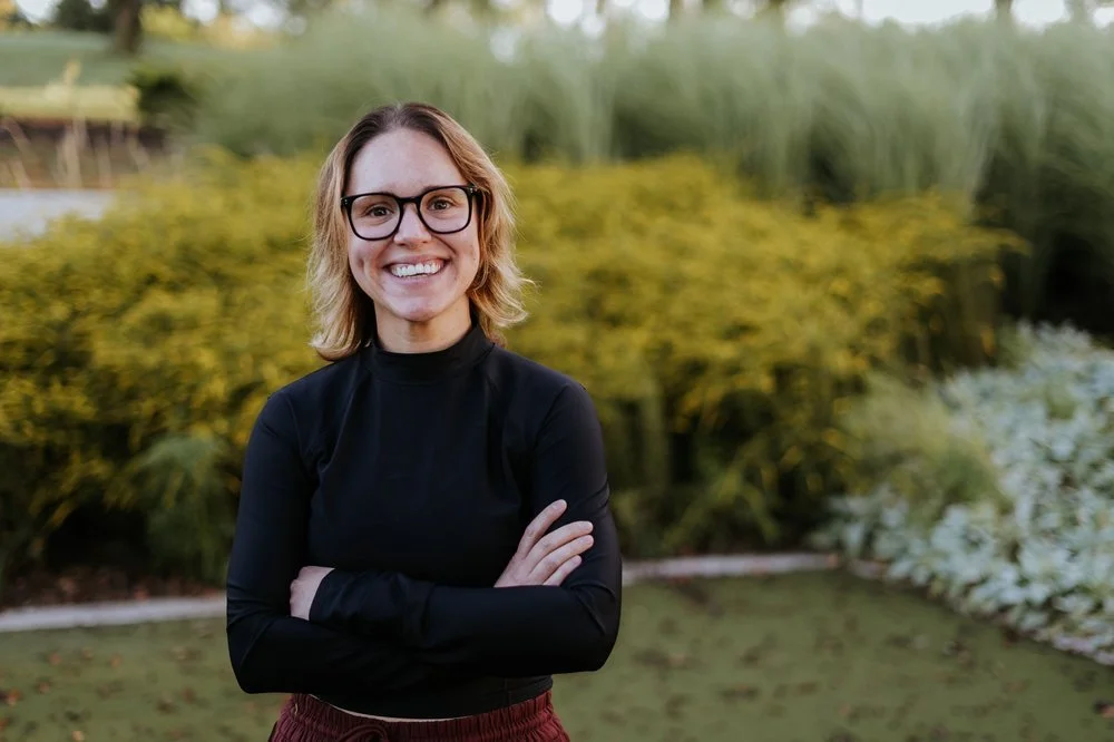 Amber Harris, somatic coach and guide, smiling warmly in a portrait photo