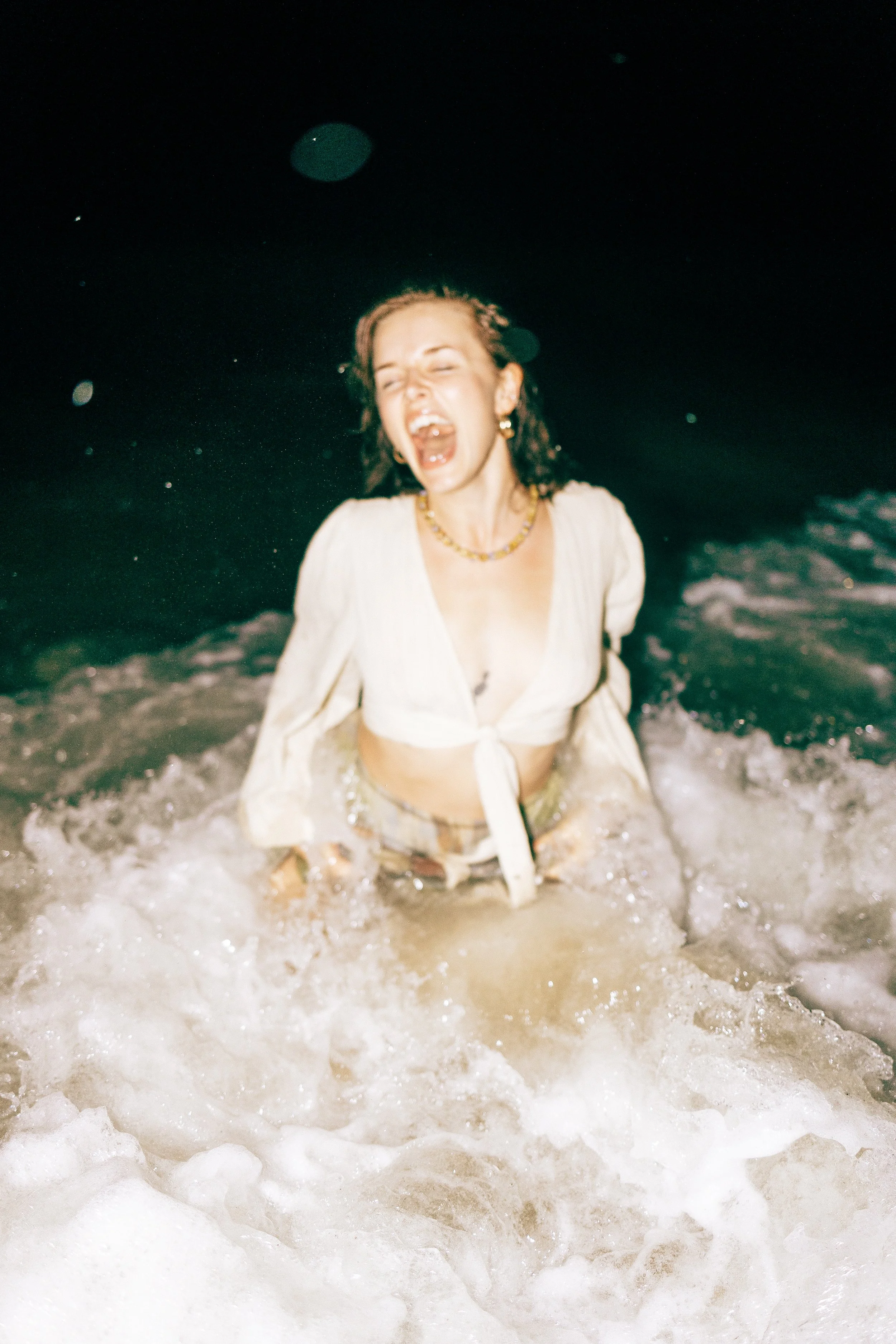 Cally Sky beautiful A woman standing in the ocean at night, laughing and splashing water. nashville billboard photographer, top lifestyle nashville photographer, brand photographer nashville Katie Coffee