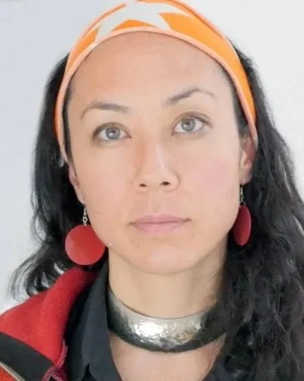 Marissa Jahn has light skin, dark hair, a bandana, dangly earrings, a silver necklace