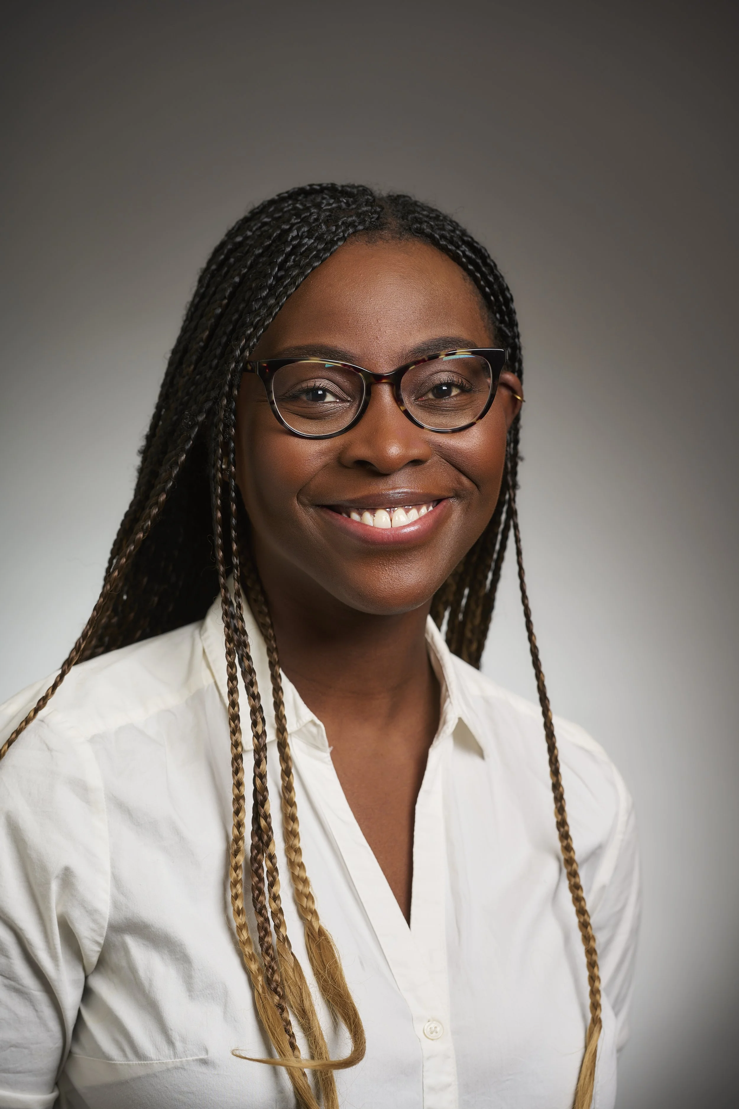 A headshot of Vanessa Nyarko, a Black woman with glasses wearing a white blouse