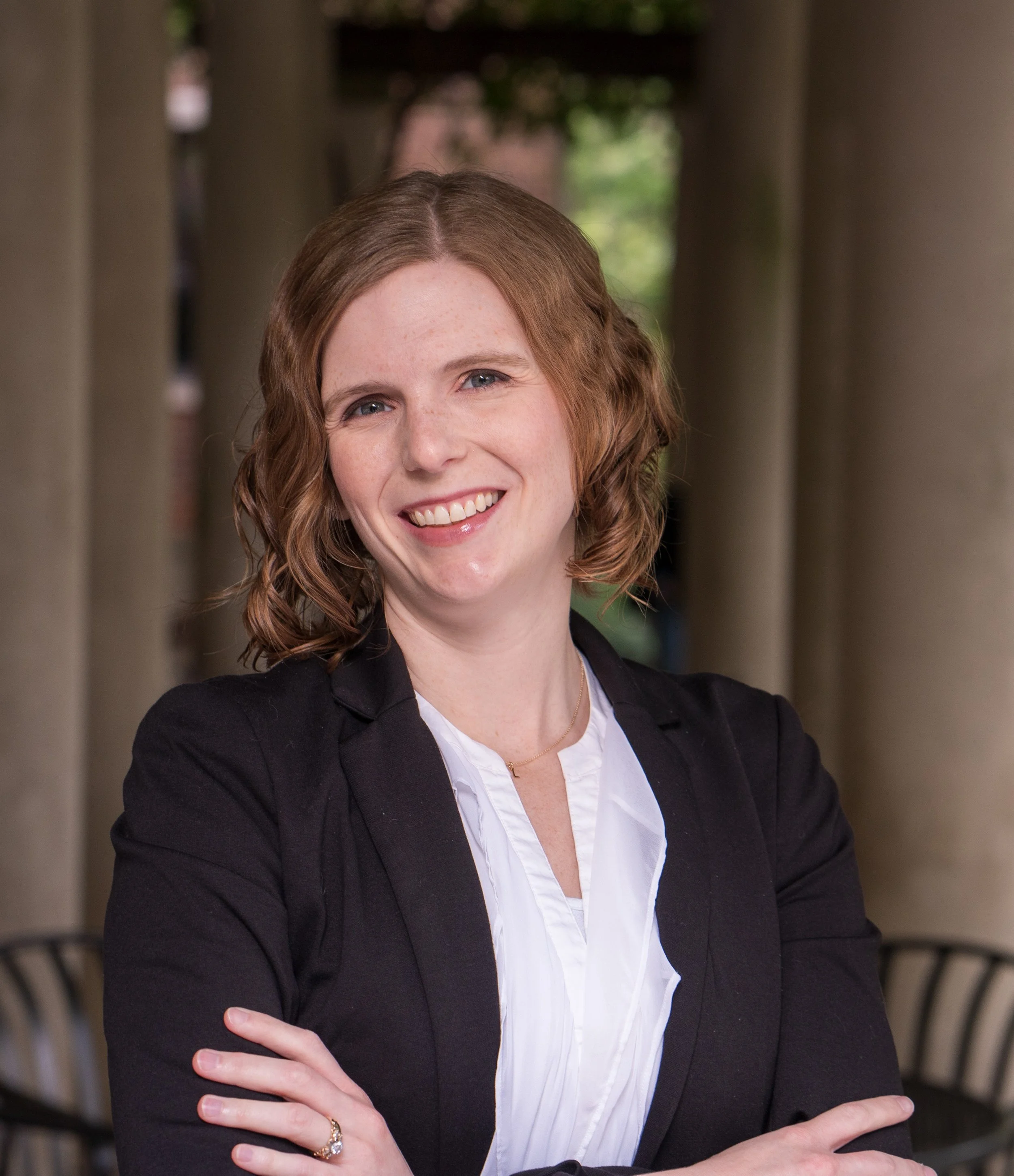 A headshot of Lucy March, a white woman with ginger hair wearing a blazer and smiling at the camera.