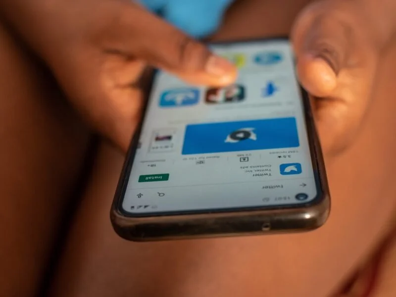 A phone is being held by two hands, showing social media apps